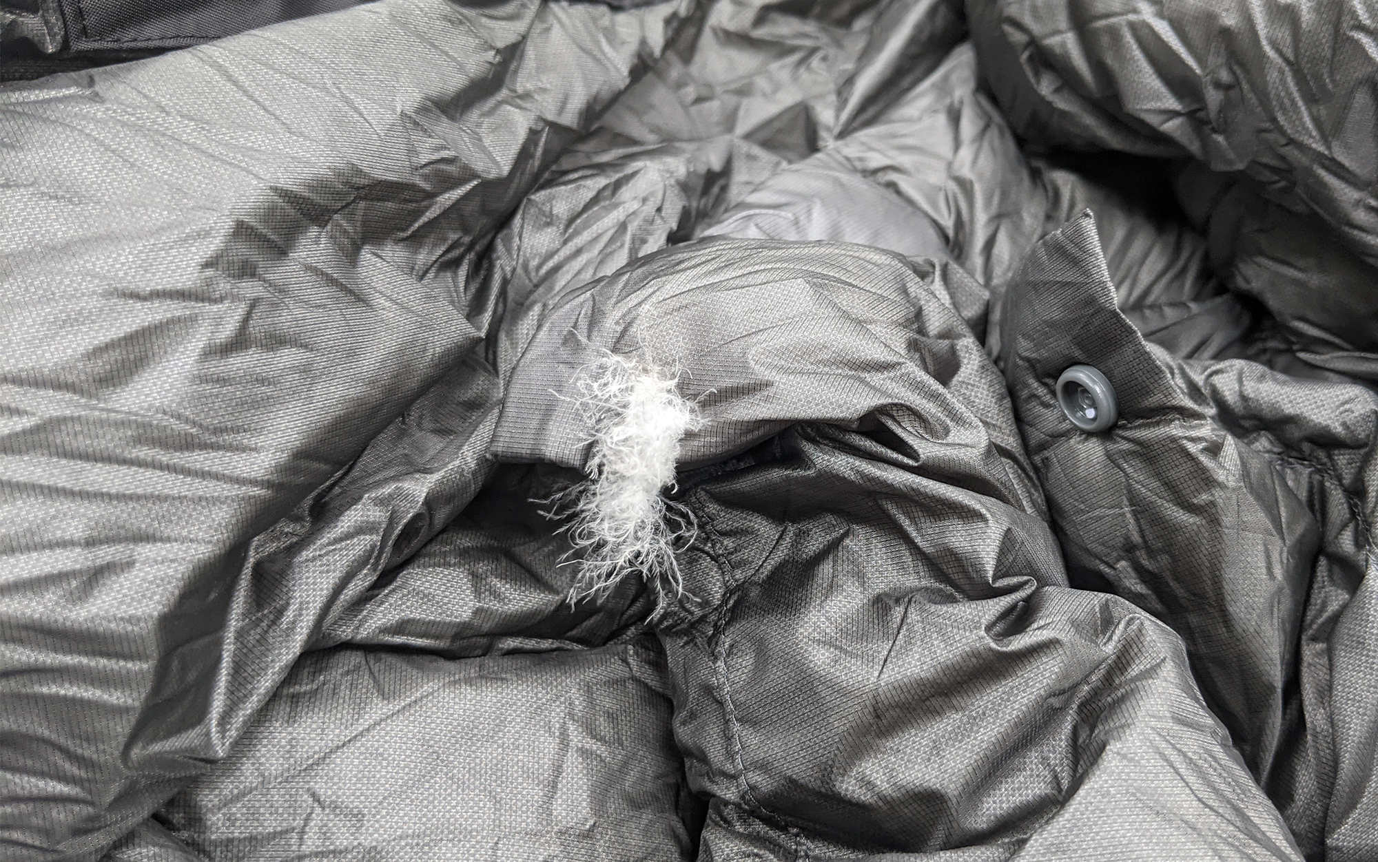 Kuiu SuperDown Altai sleeping bag fabric tear with exposed down plumes