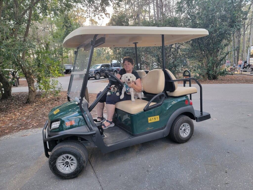 A woman in a golf cart holding her dog at Fort Wilderness.