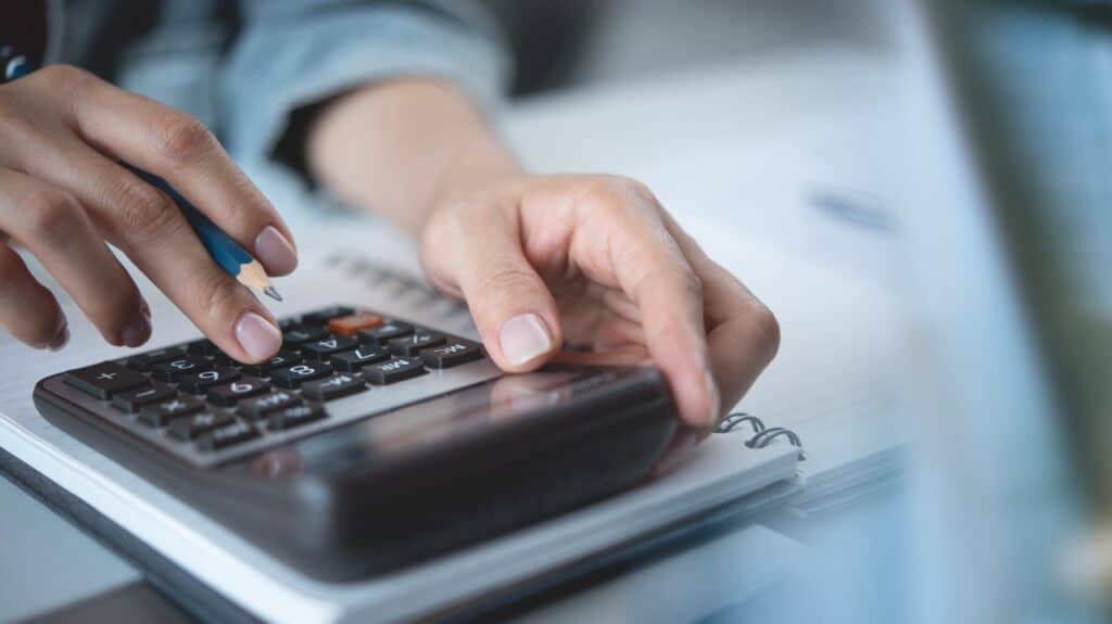 Hands working a calculator. Photo: Shutterstock.