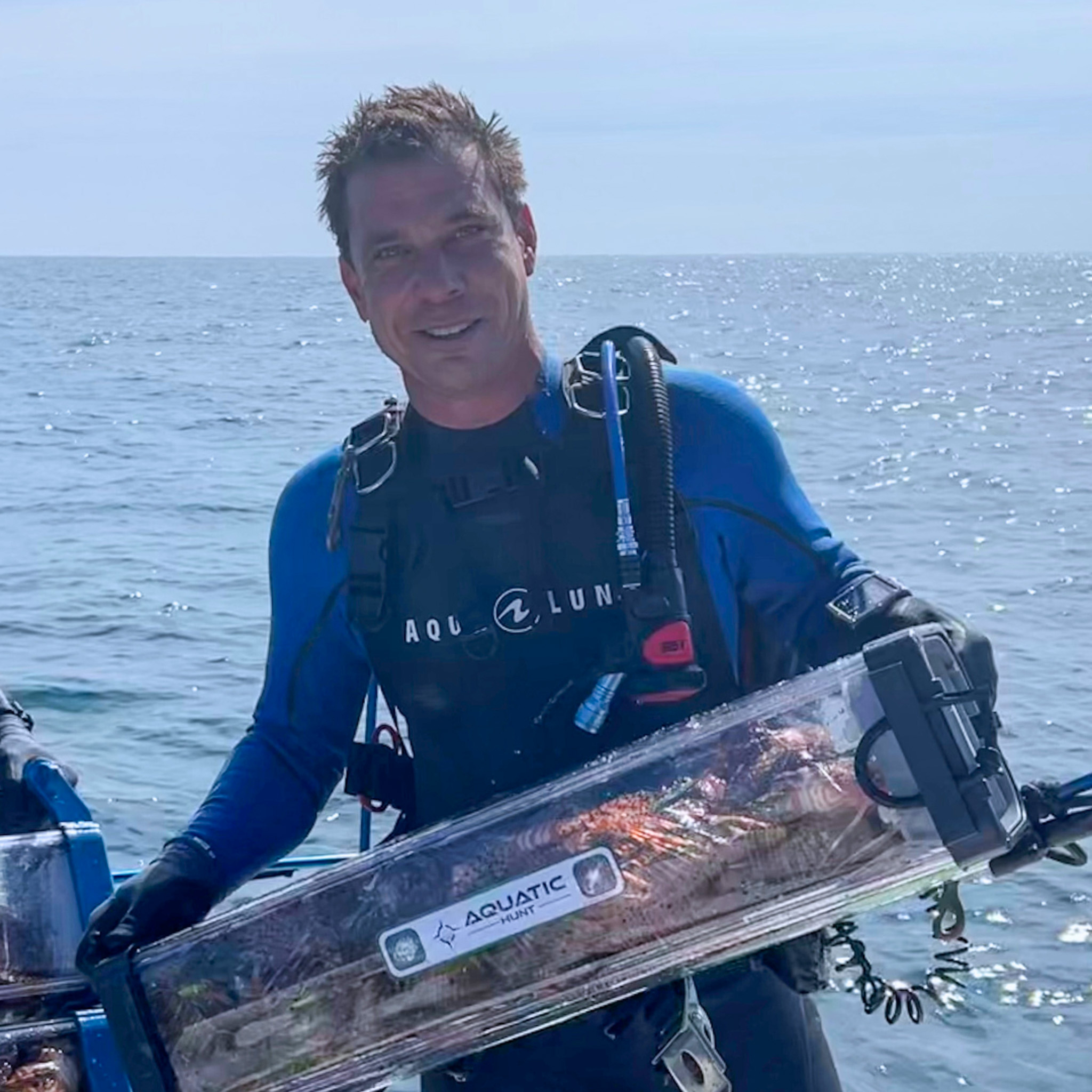 A diver with lionfish in a creel