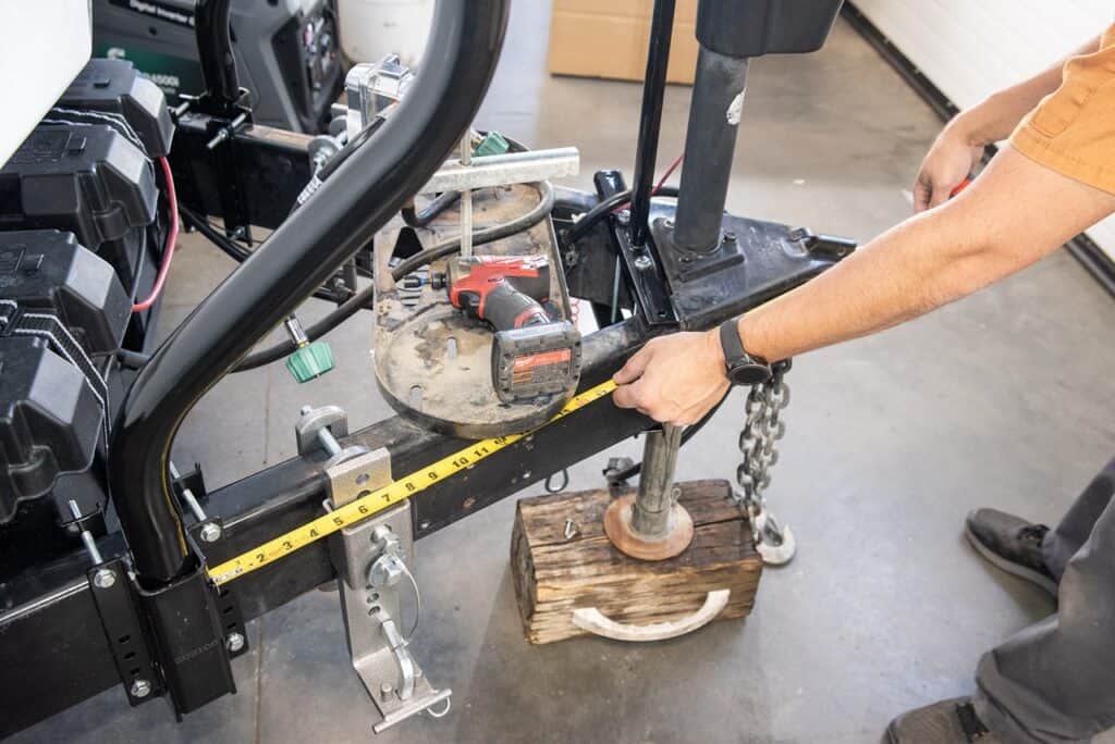 The bottom support brackets need to be equal distance from the trailer hitch. Here, the installer uses the ball lock as his reference point.