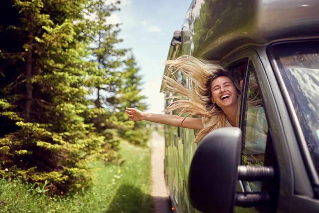 A woman with her head out the window of a Class C motorhome. Photo: Shutterstock,.