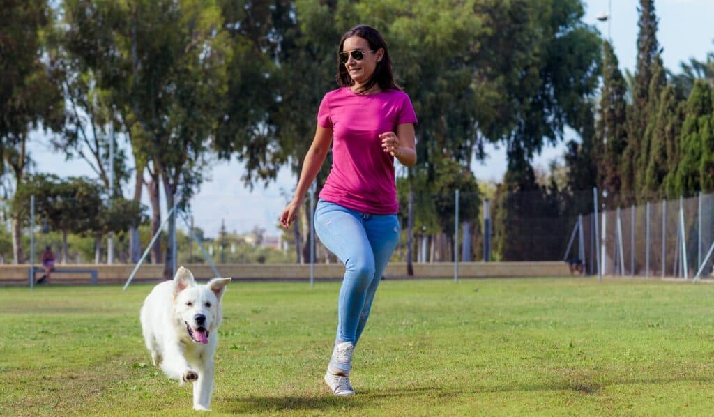 Woman and dog running and having fun at a dog park