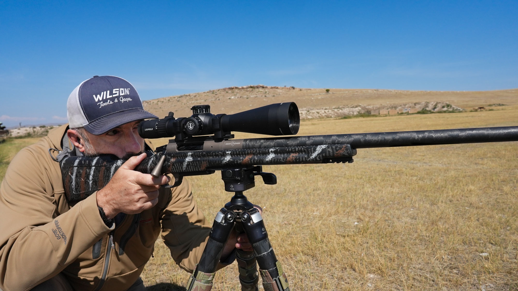 a man in a brown jacket shoots the Mack Brothers Custom Rifle at range