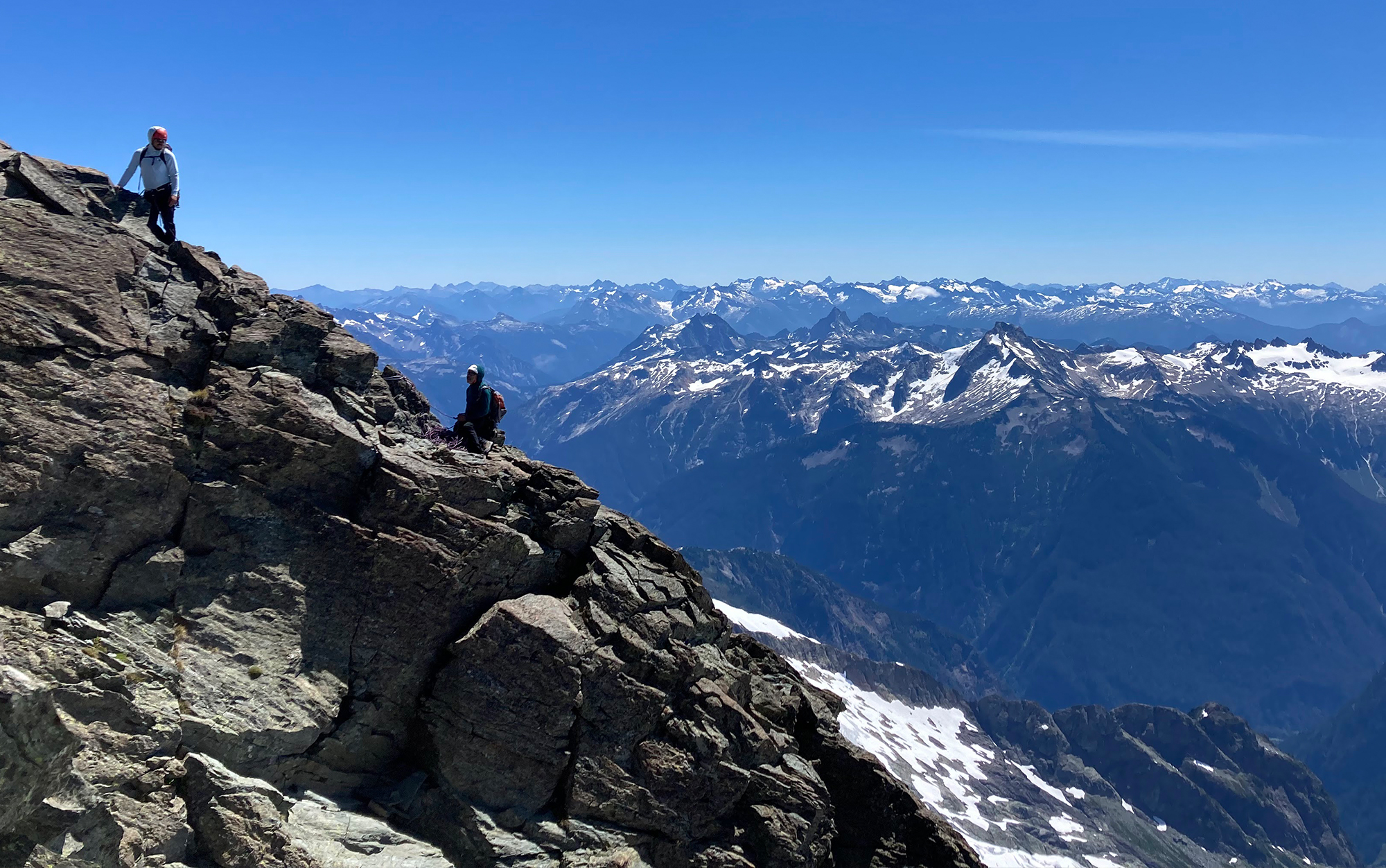 Climbers sit on ridge.