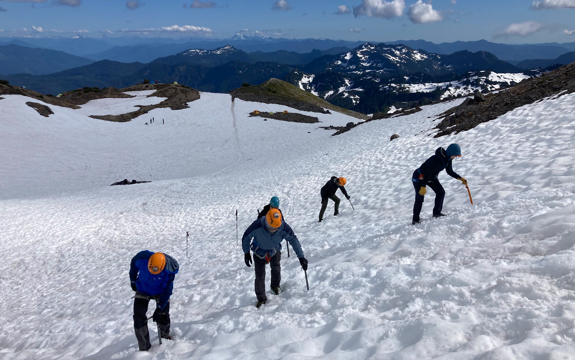 Mountaineers climb a snowfield. 