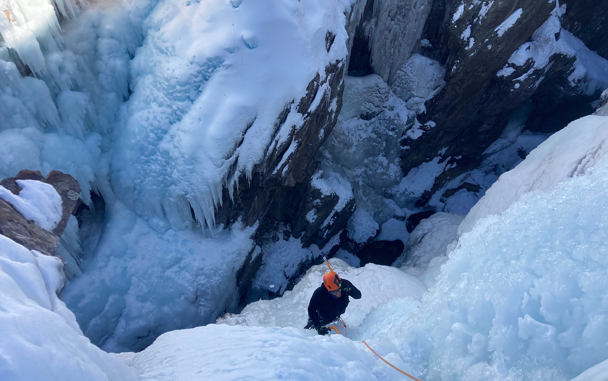 Ice climber ascends with ice ax.