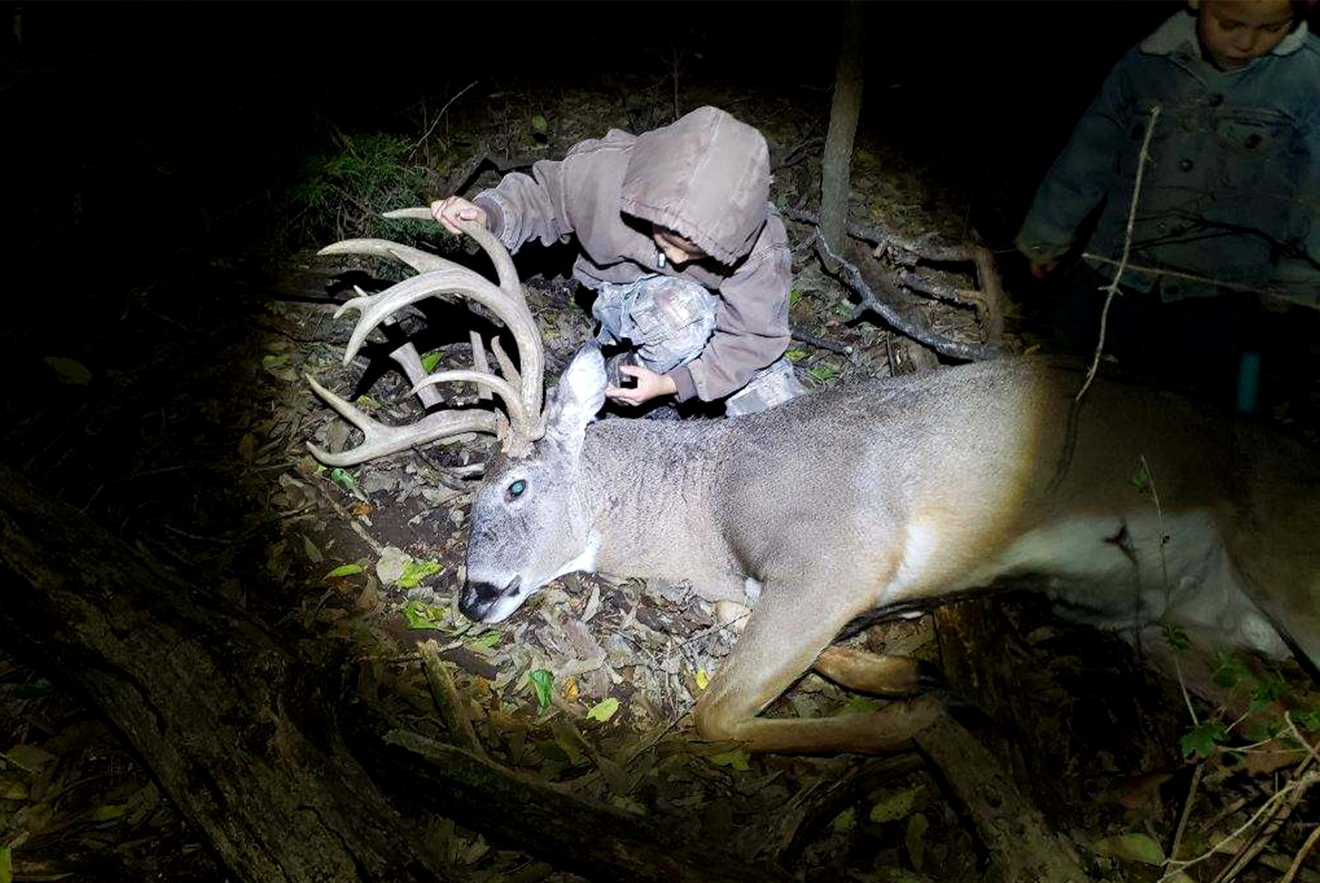 A youth hunter looks over his first buck.