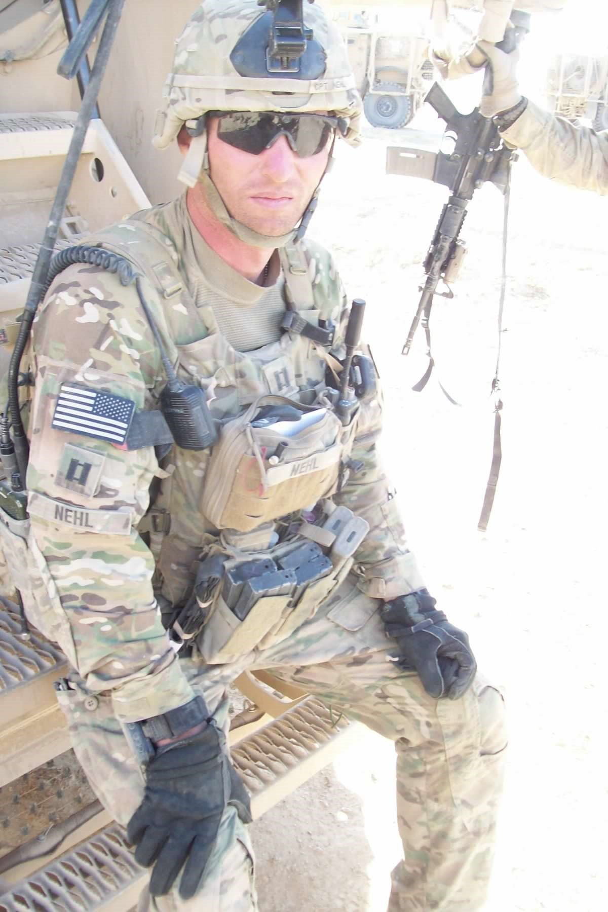 A soldier in full combat gear looks at the camera.