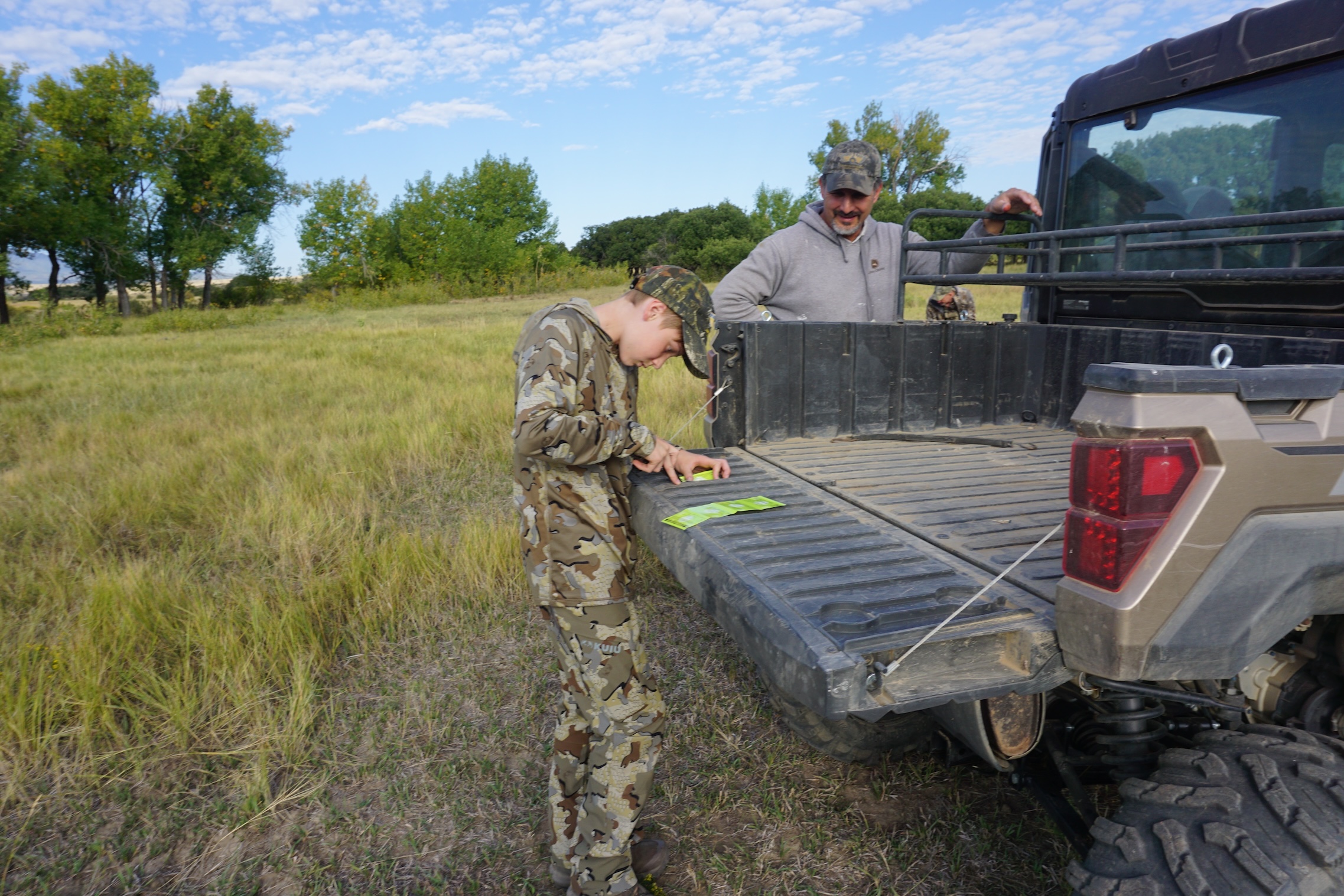 A young hunter punches a tag on the back of an ATV.