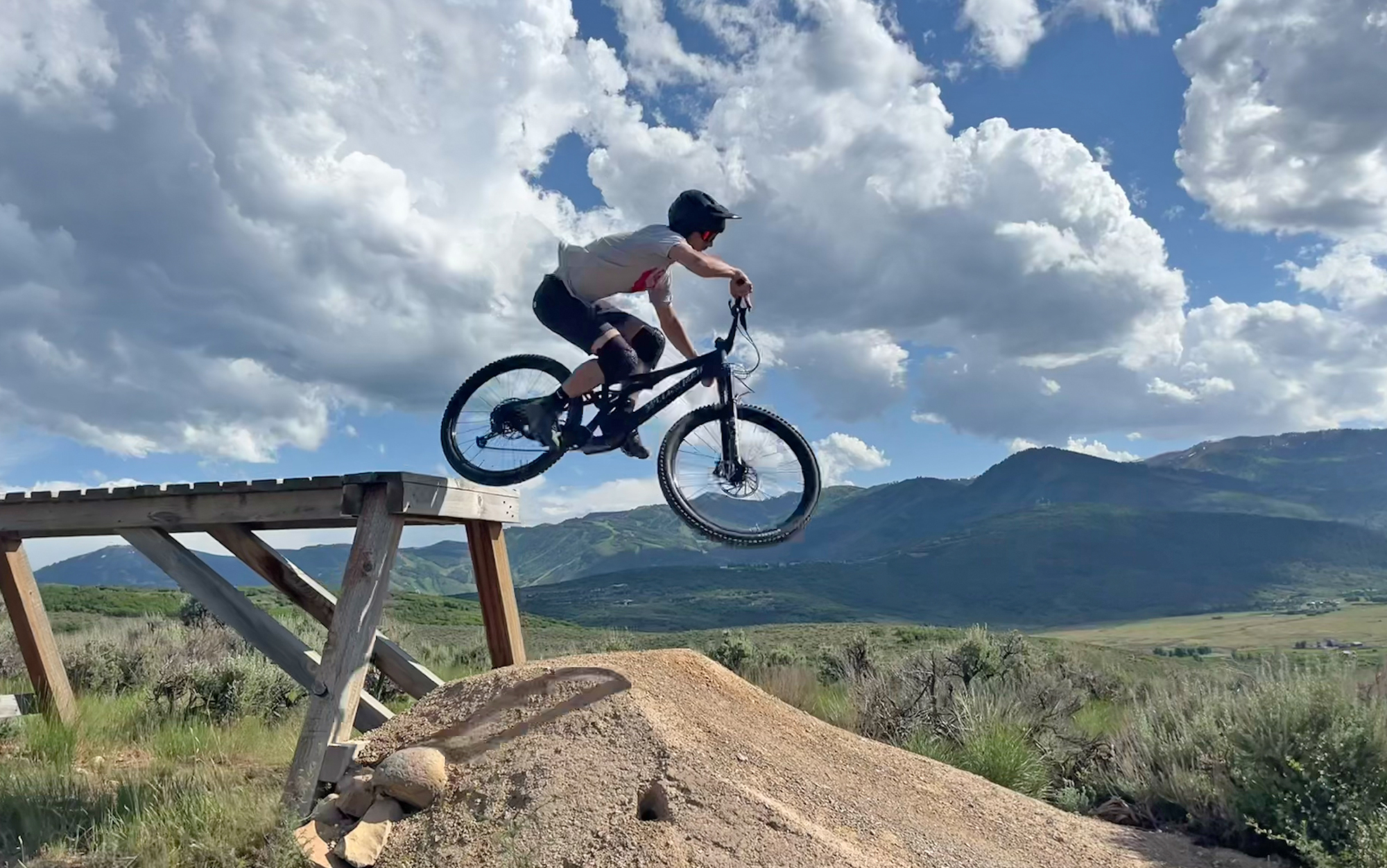 Biker goes off a wooden drop feature.