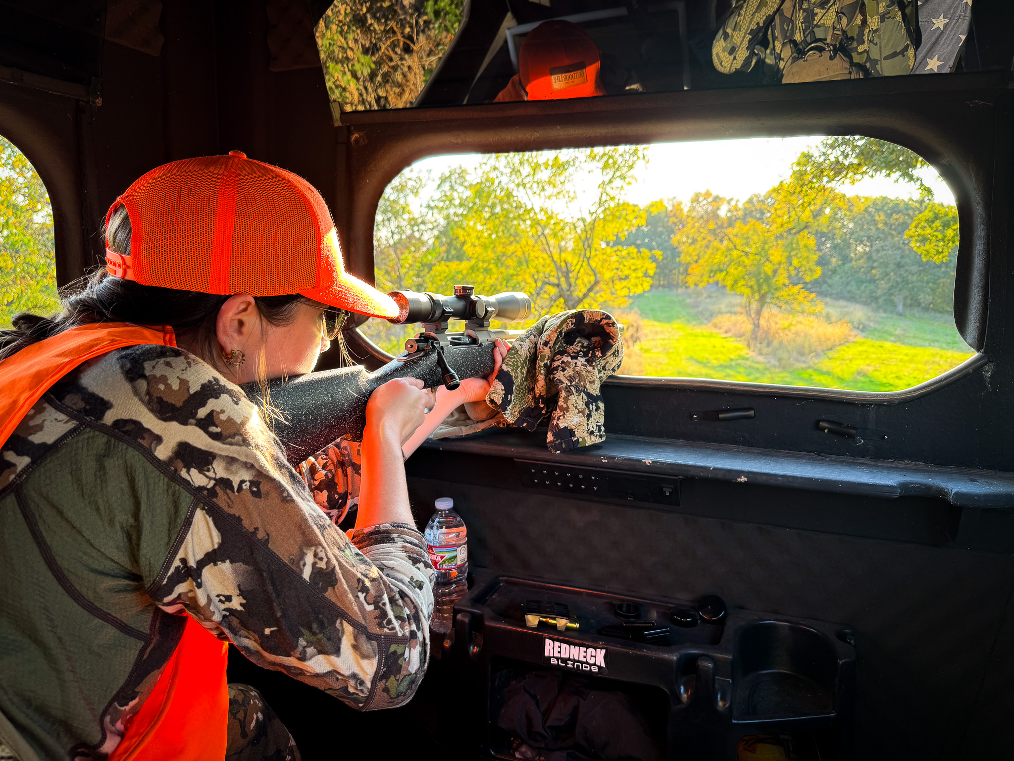 A hunter aims out of a blind.