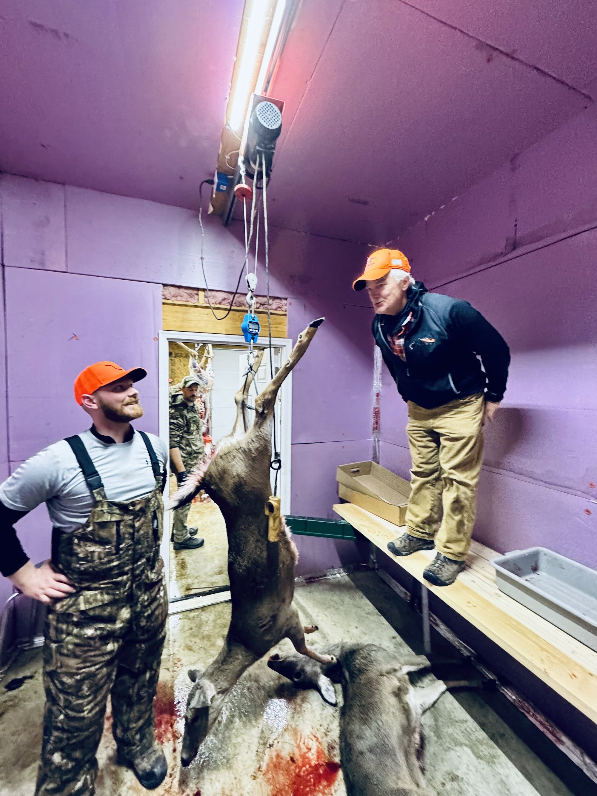 Two hunters goof around in a walk in cooler.