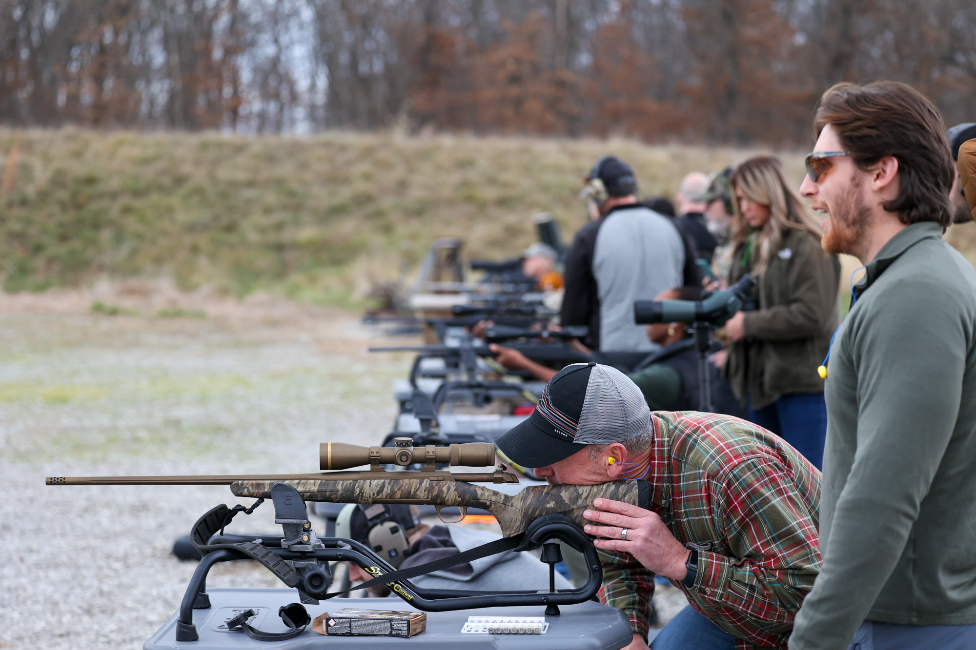 A man looks through the scope of the rifle at the range.