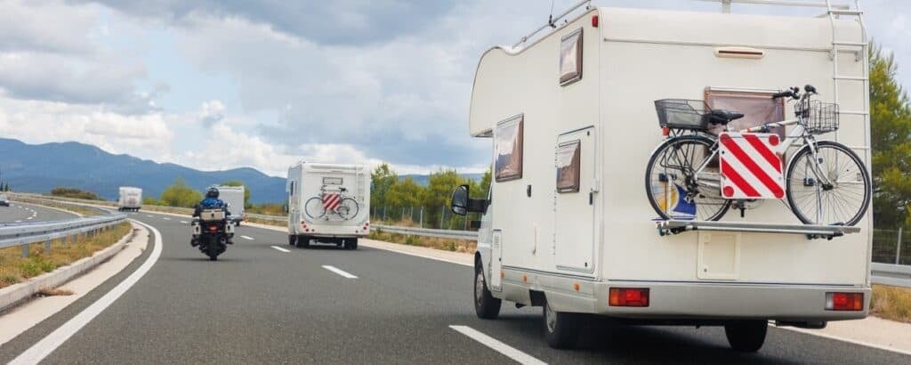 A motorcycle on the road with a couple of Class C motorhomes. Photo: Shutterstock.