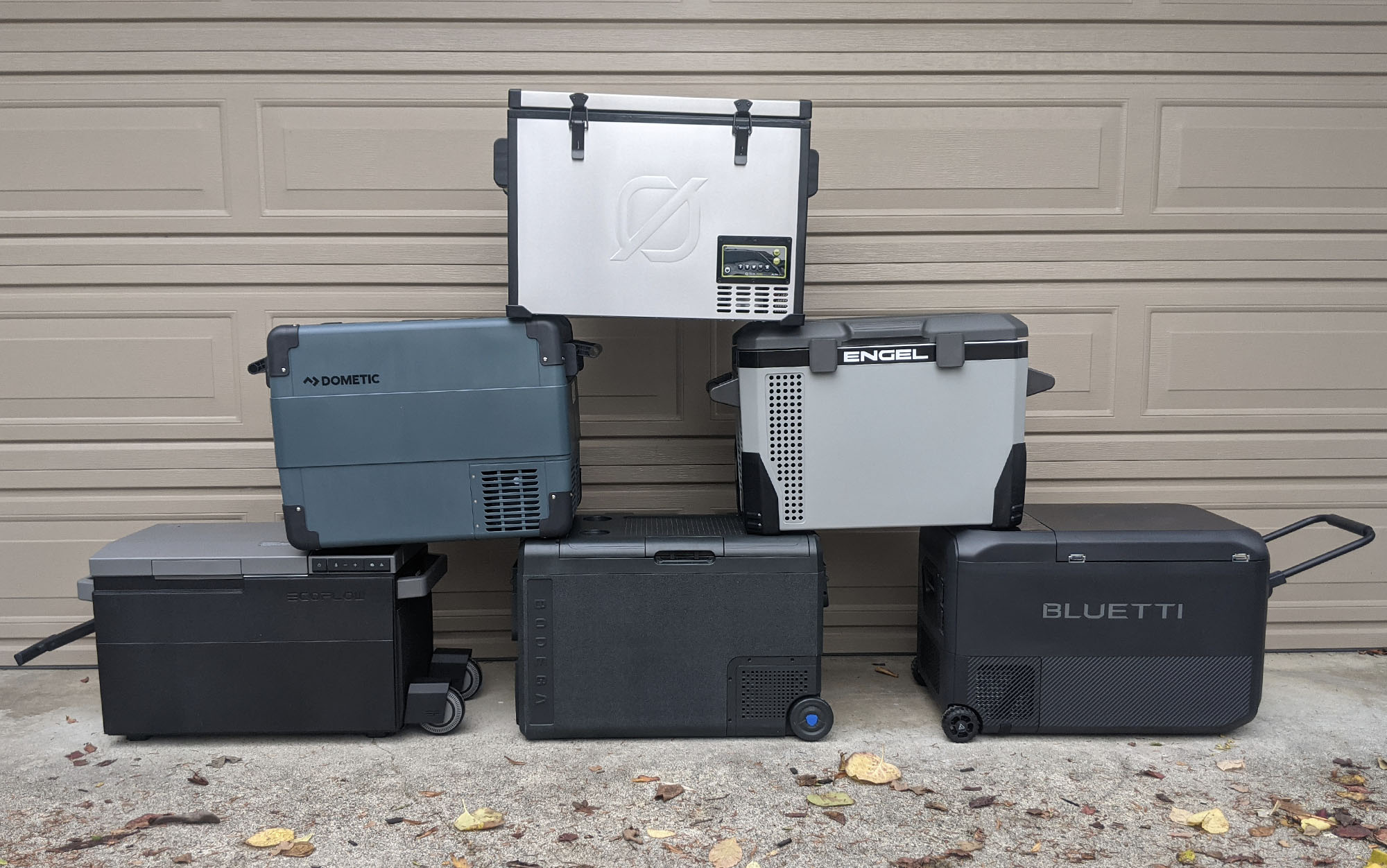 six electric coolers stacked on top of each other in front of a garage