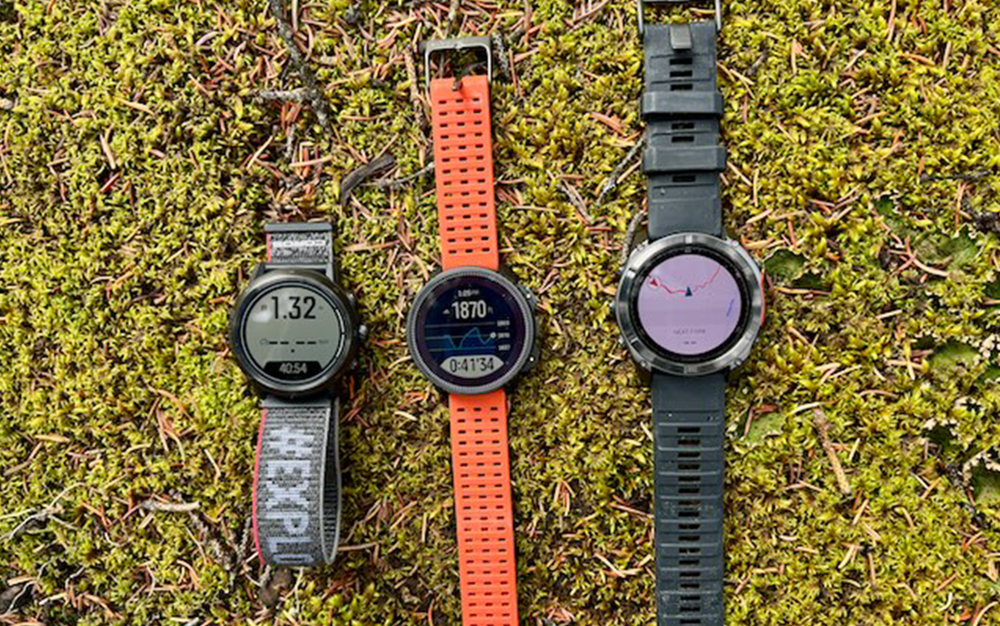 Three smartwatches sit on moss.