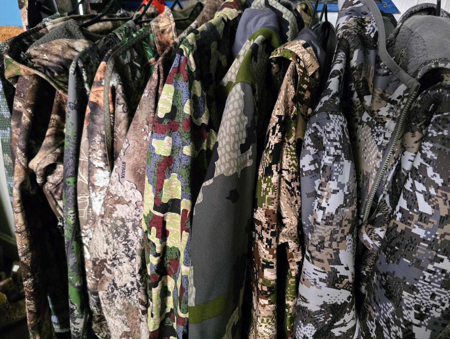 A clothing rack full of hunting jackets in different camo patterns