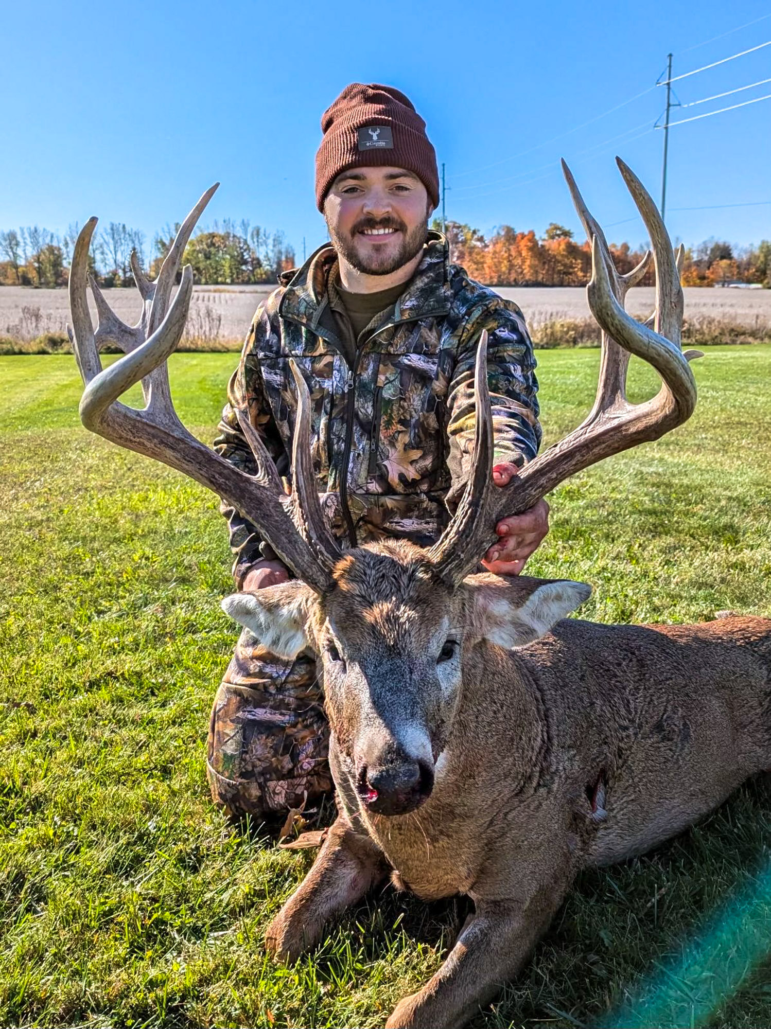 A hunter with a giant typical buck with stickers.