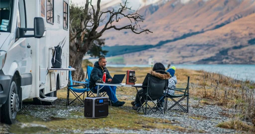 family camping by the lake with devices plugged into Bluetti portable power station