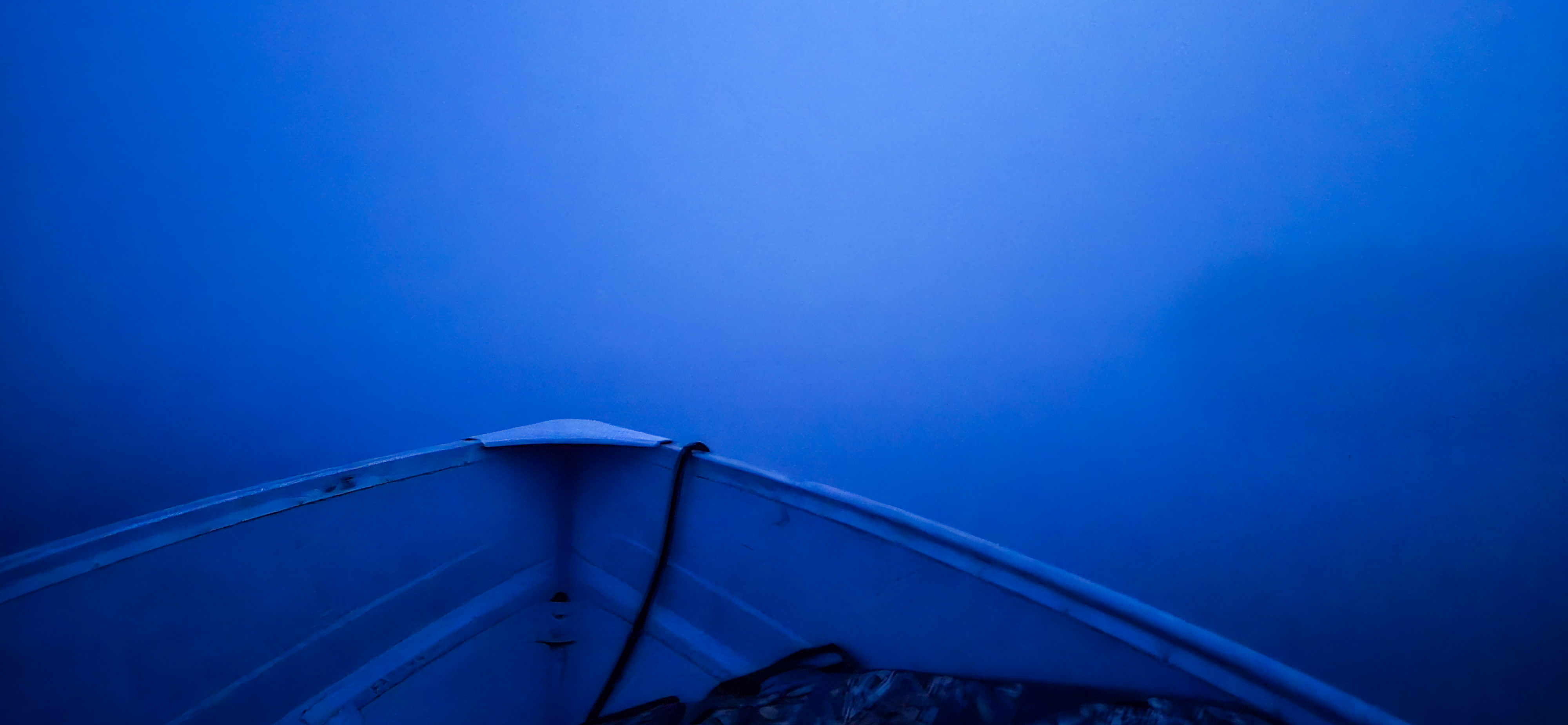 The bow of a boat in a blue fog.