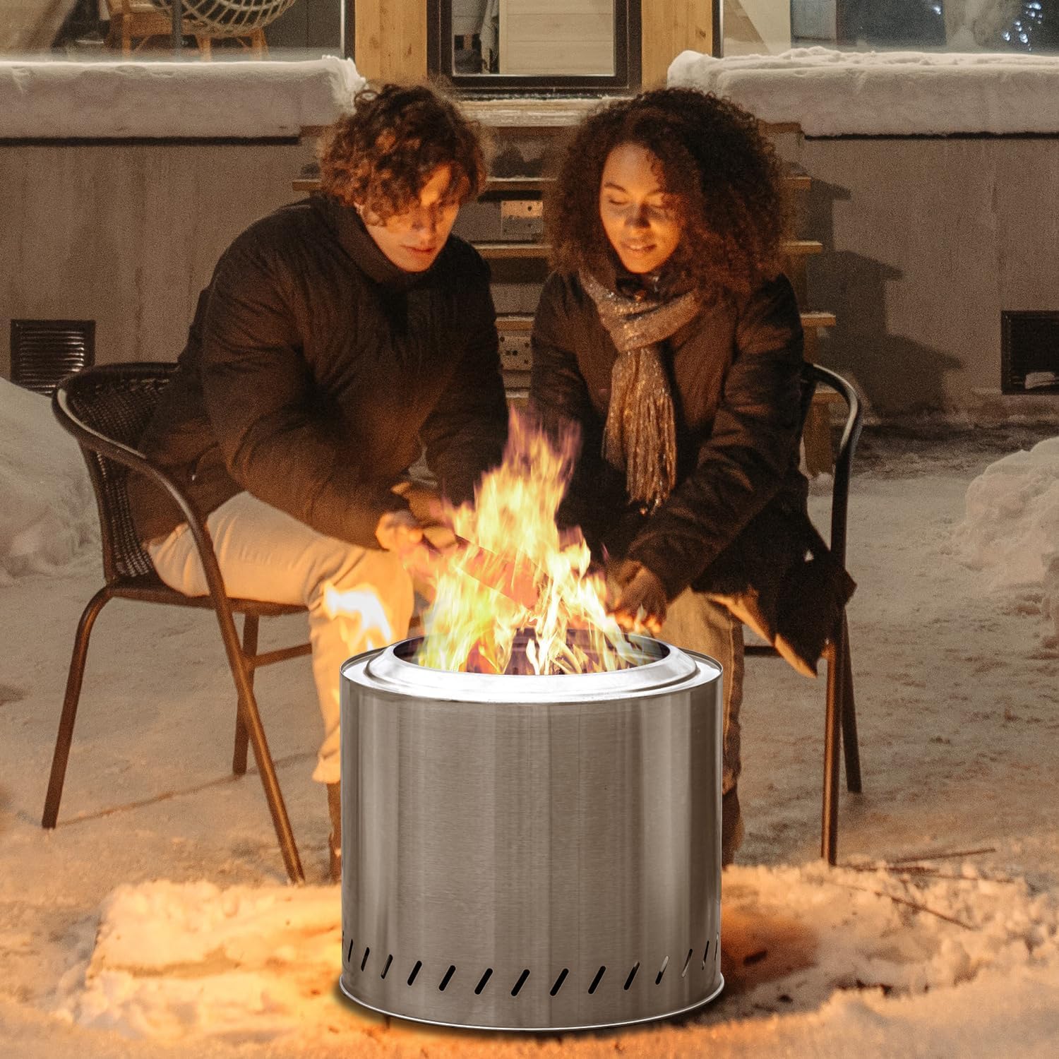 Two people warming by a portable fire pit.