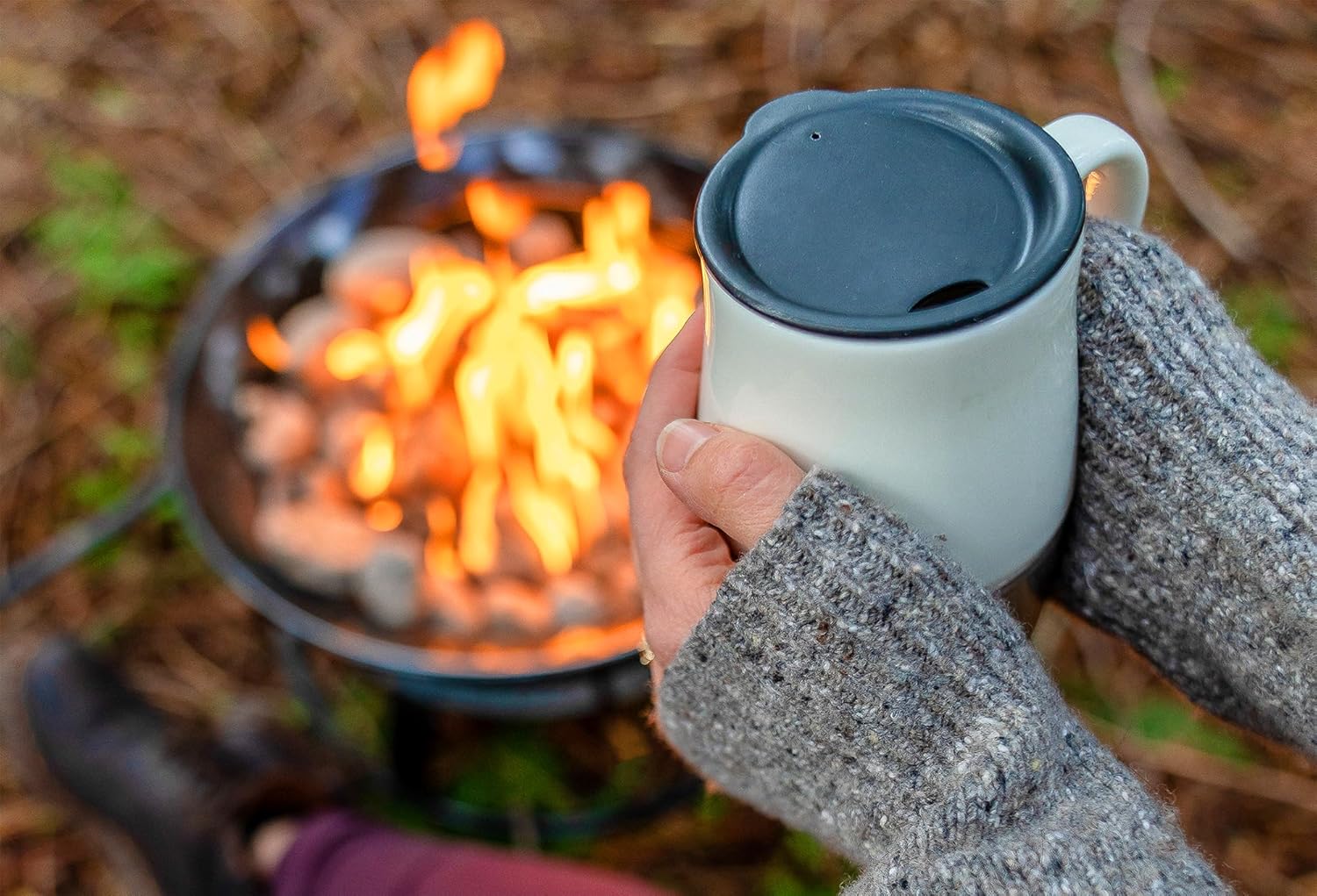 Hands warming on a mug by the fire.