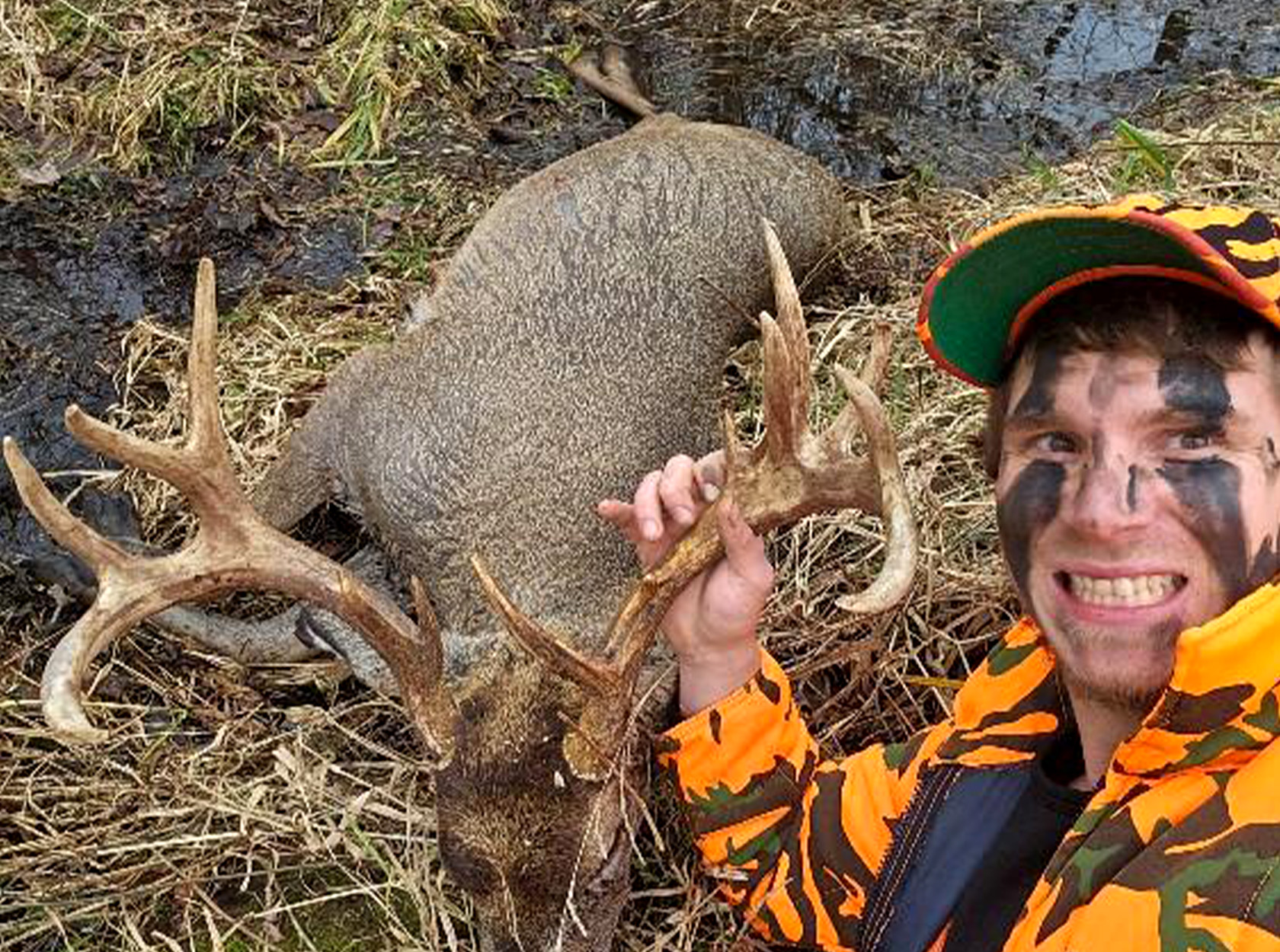 A hunter takes a selfie with a buck.