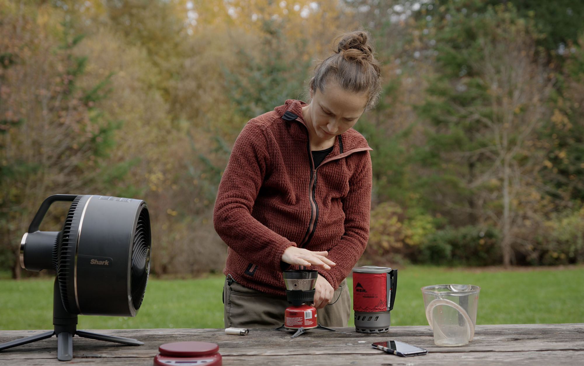 woman lighting a canister stove system on a picnic table