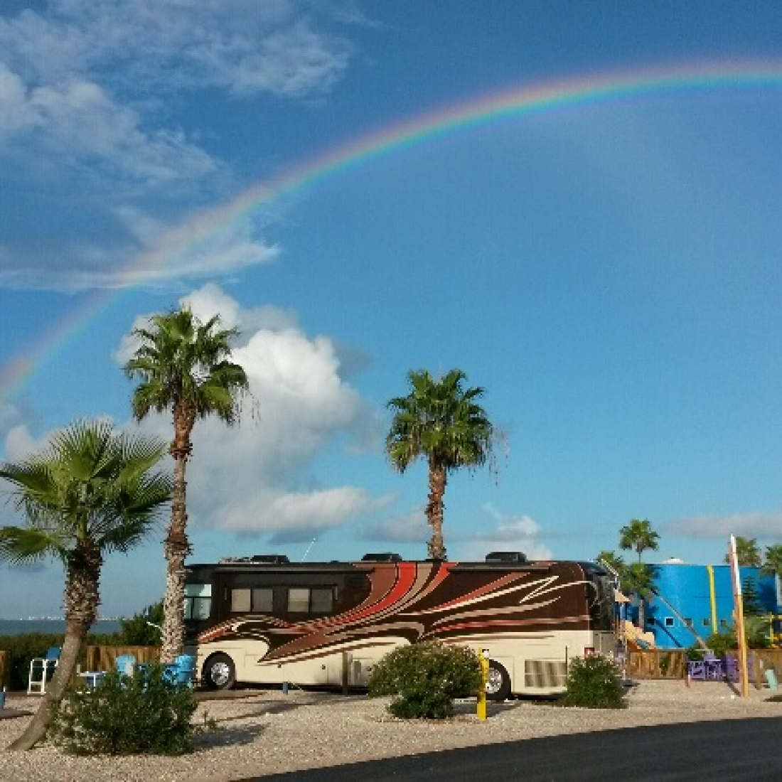 Motorhome in a campsite with a rainbow overhead at South Padre Island KOA Holiday.