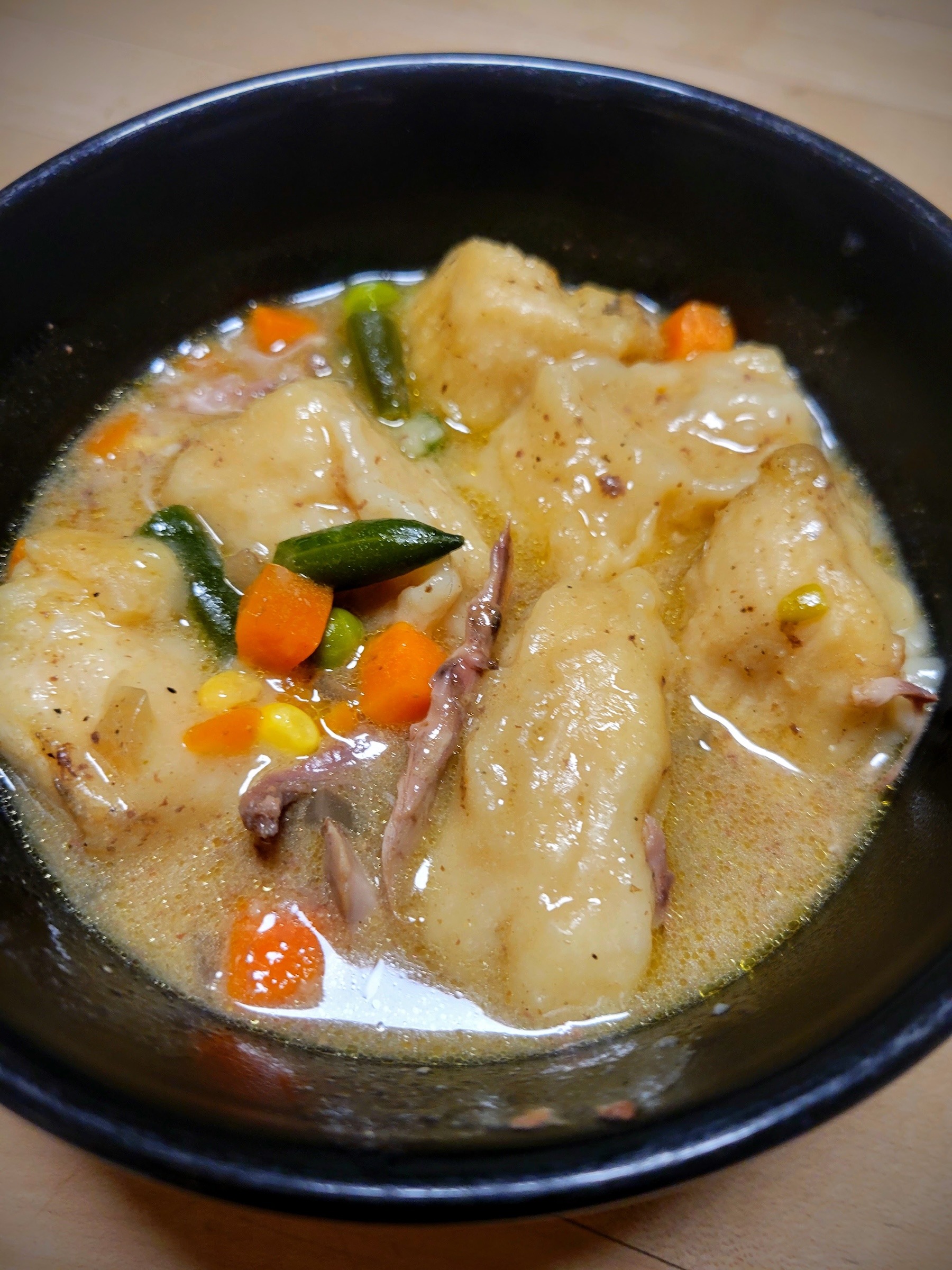 A bowl of hearty squirrel stew with vegetables and dumplings.