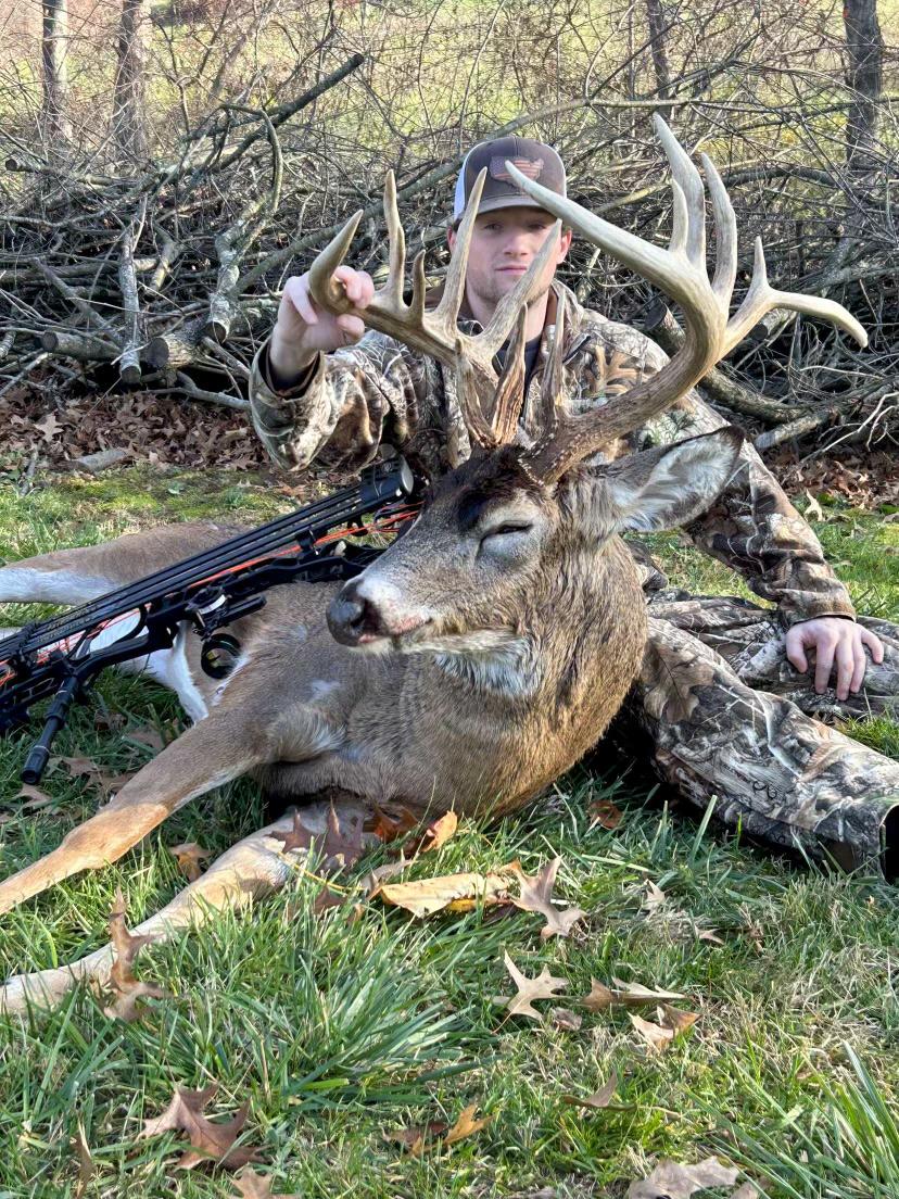 A bowhunter sits behind a big buck.