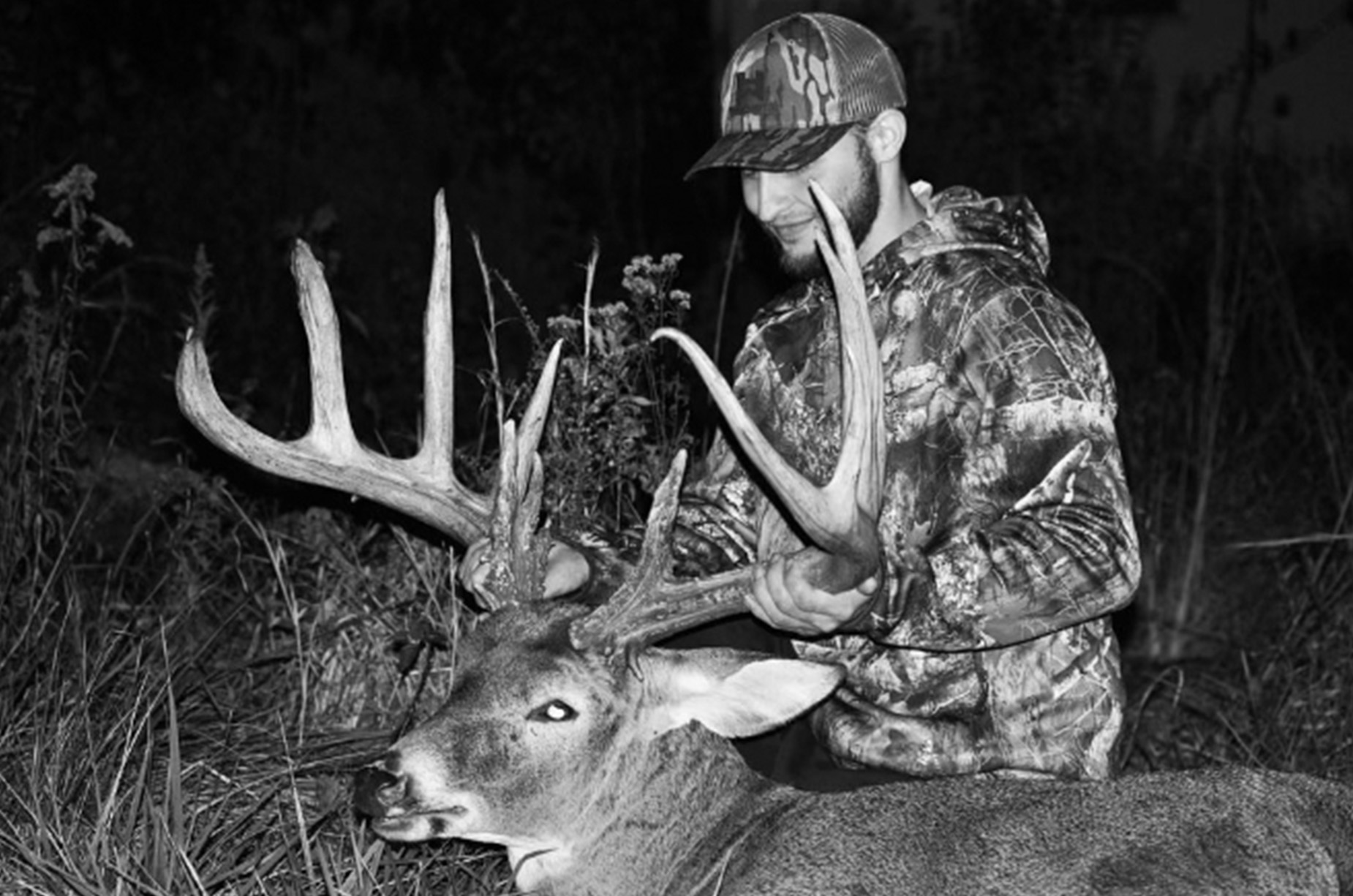 A black-and-white photo of CJ Alexander with the giant Ohio buck he poached in 2023.