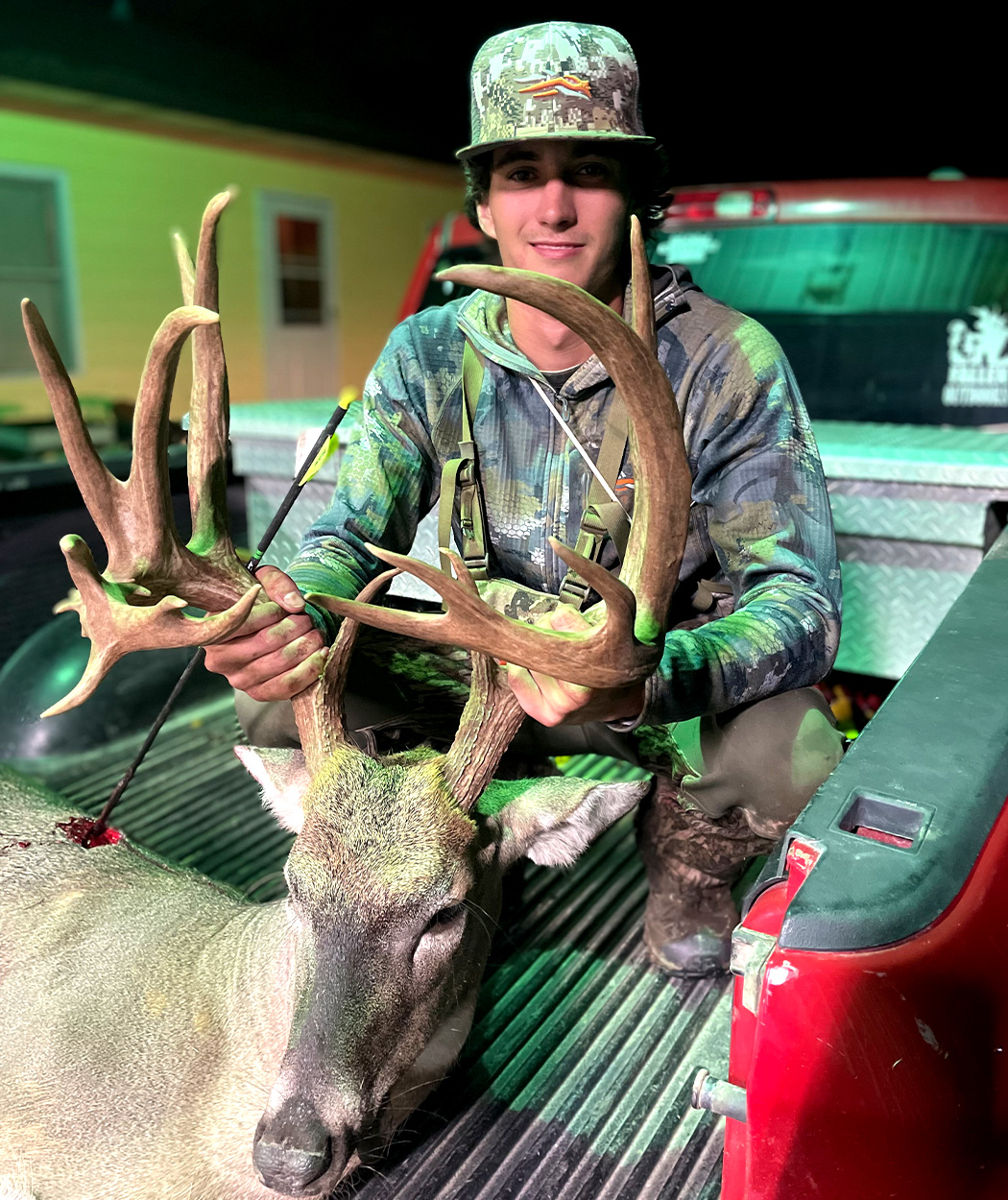 A Kansas bowhunter holds up a buck in a pickup.