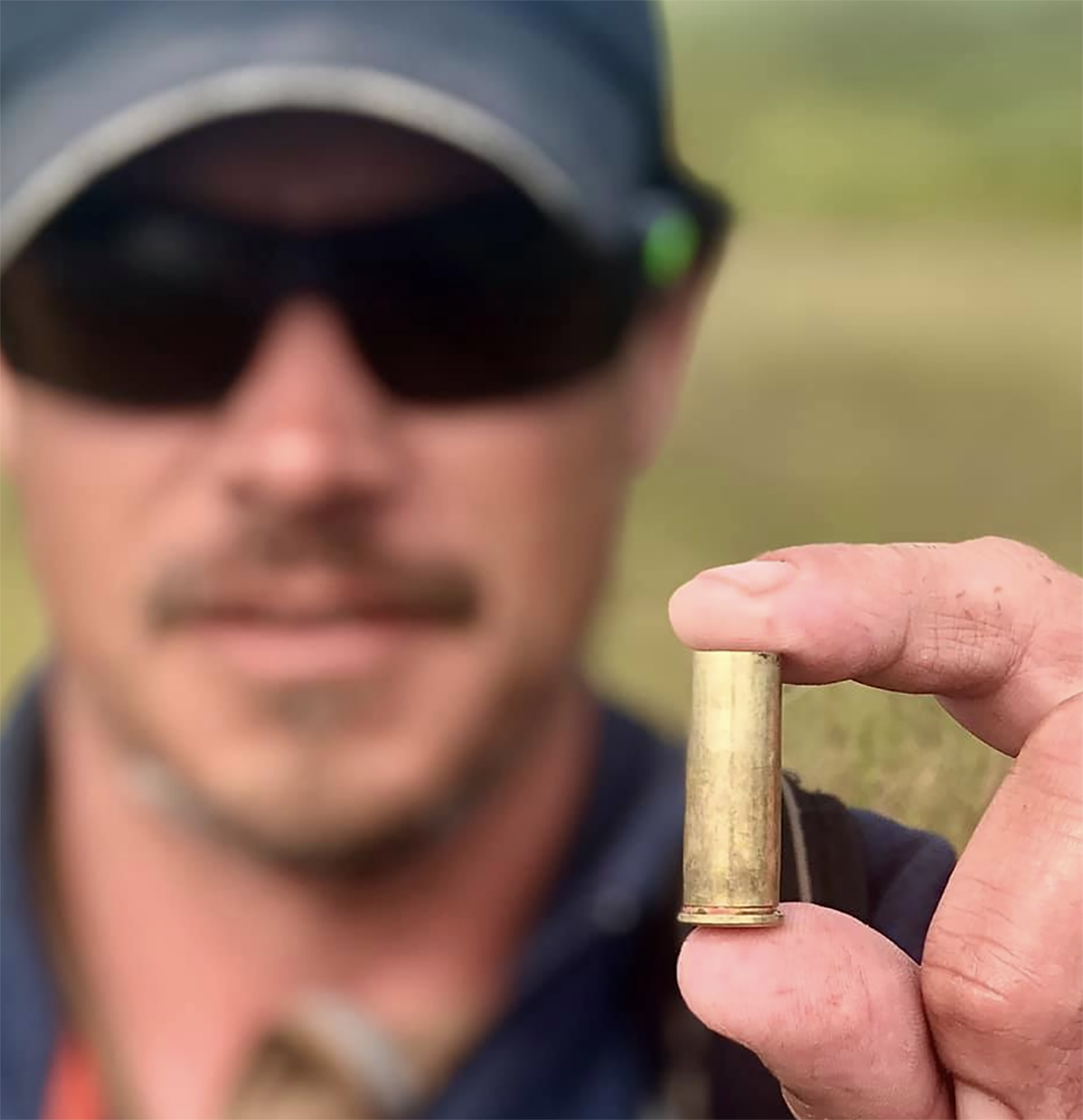 A man holds up a spent 45 cartridge.