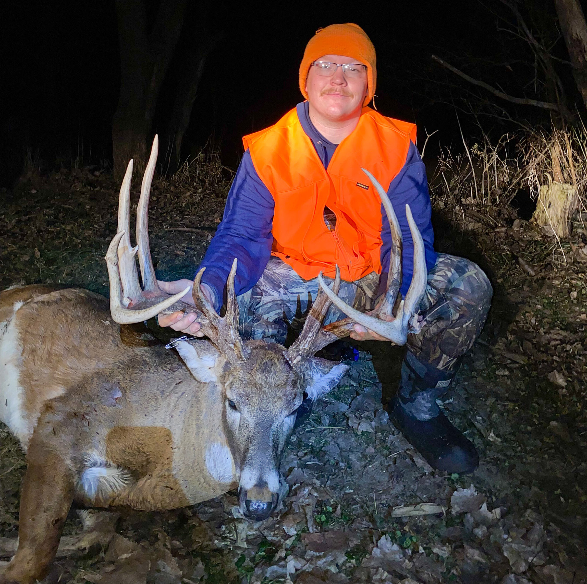 A hunter in blaze orange holds the antlers of a big Illinois buck.