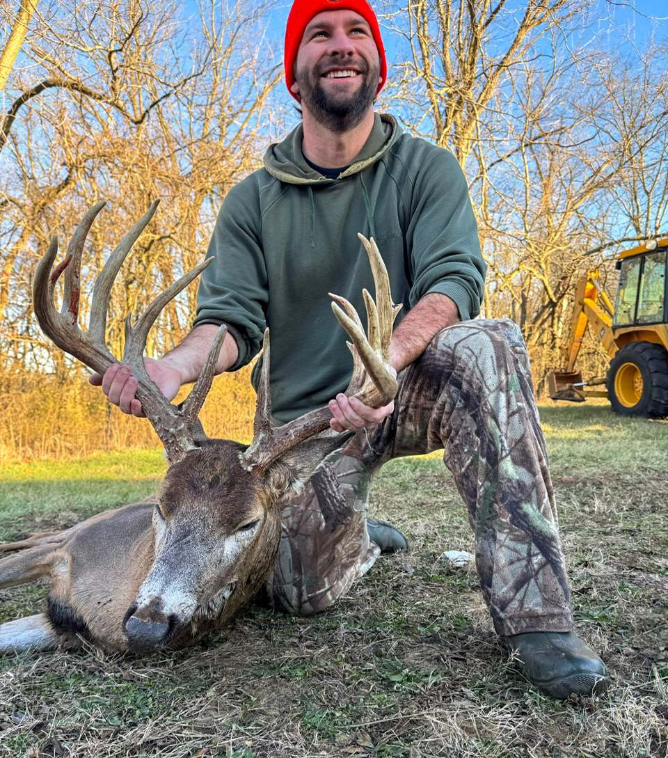 A hunter smiling while holding a big buck.