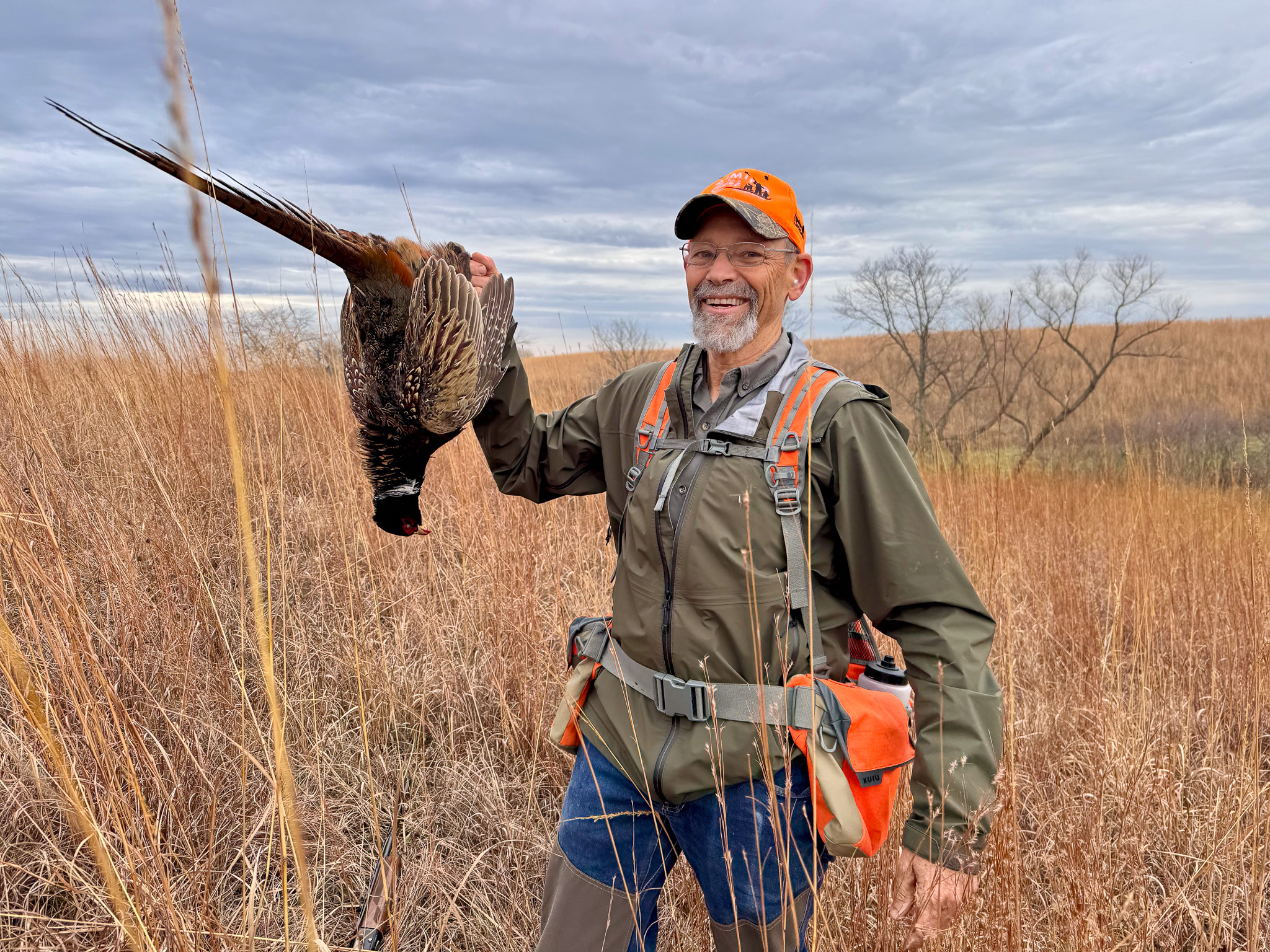 A hunter holds up a rooster.