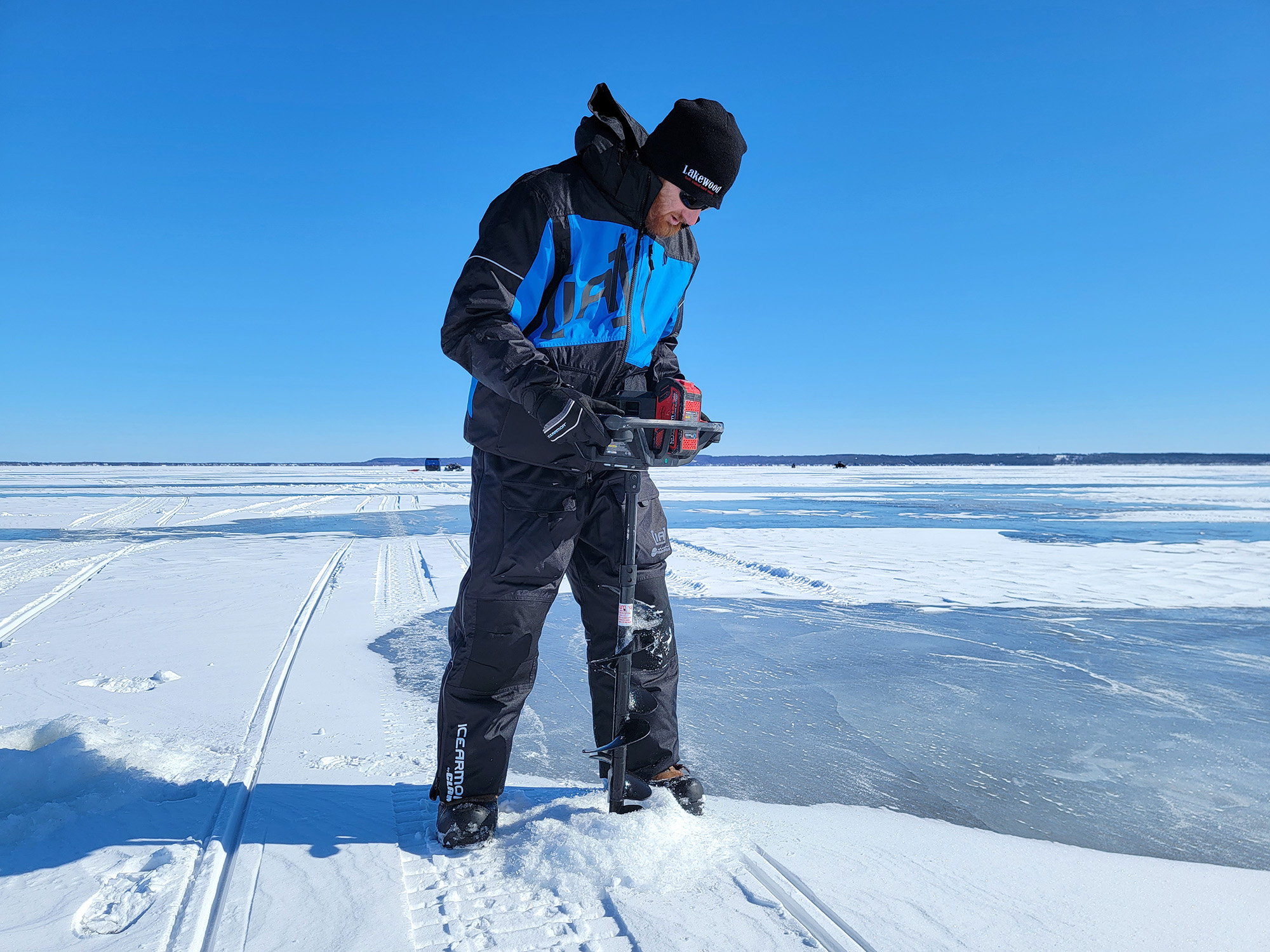 A man drills into the ice using an auger.