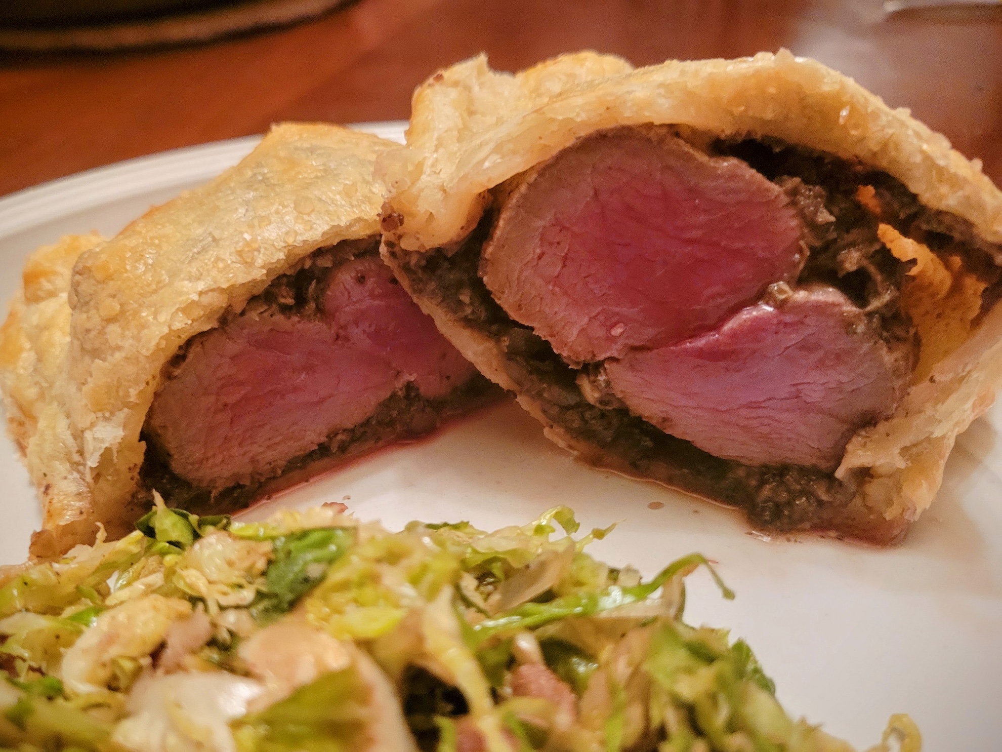 A close up of a venison Wellington sliced open and cooked medium rare.