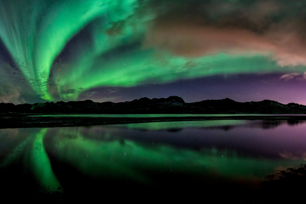 Northern lights reflecting on a lake at night - road trips in Canada