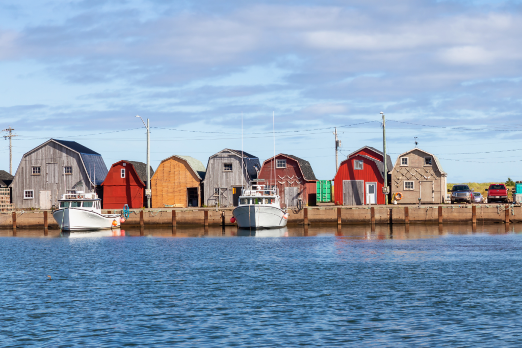 Fishing boats docked in front of small fishing shacks - road trips in Canada