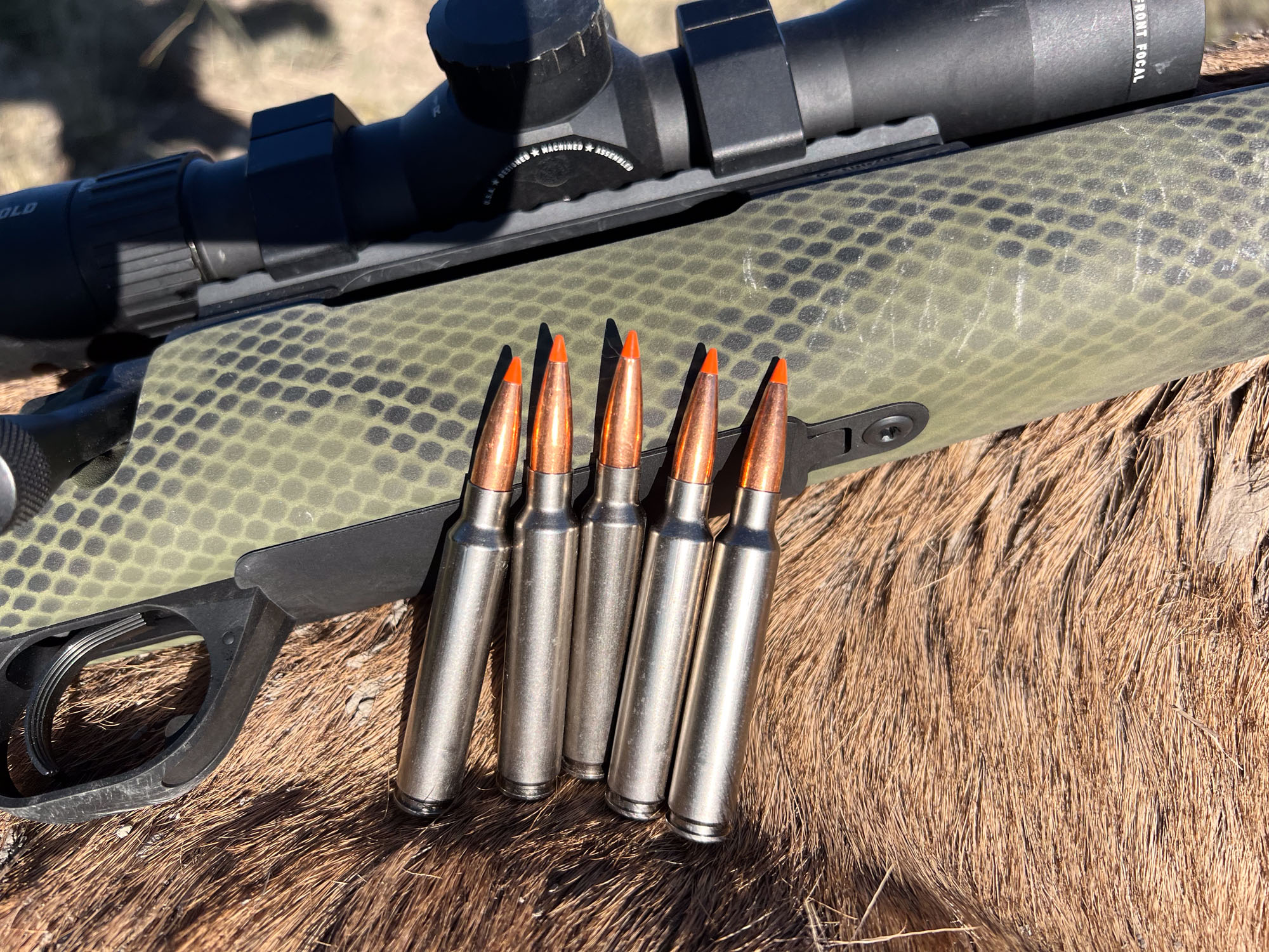 Five Federal Fusion Tipped cartridges in 7 mm BC resting on a rifle and elk hide.