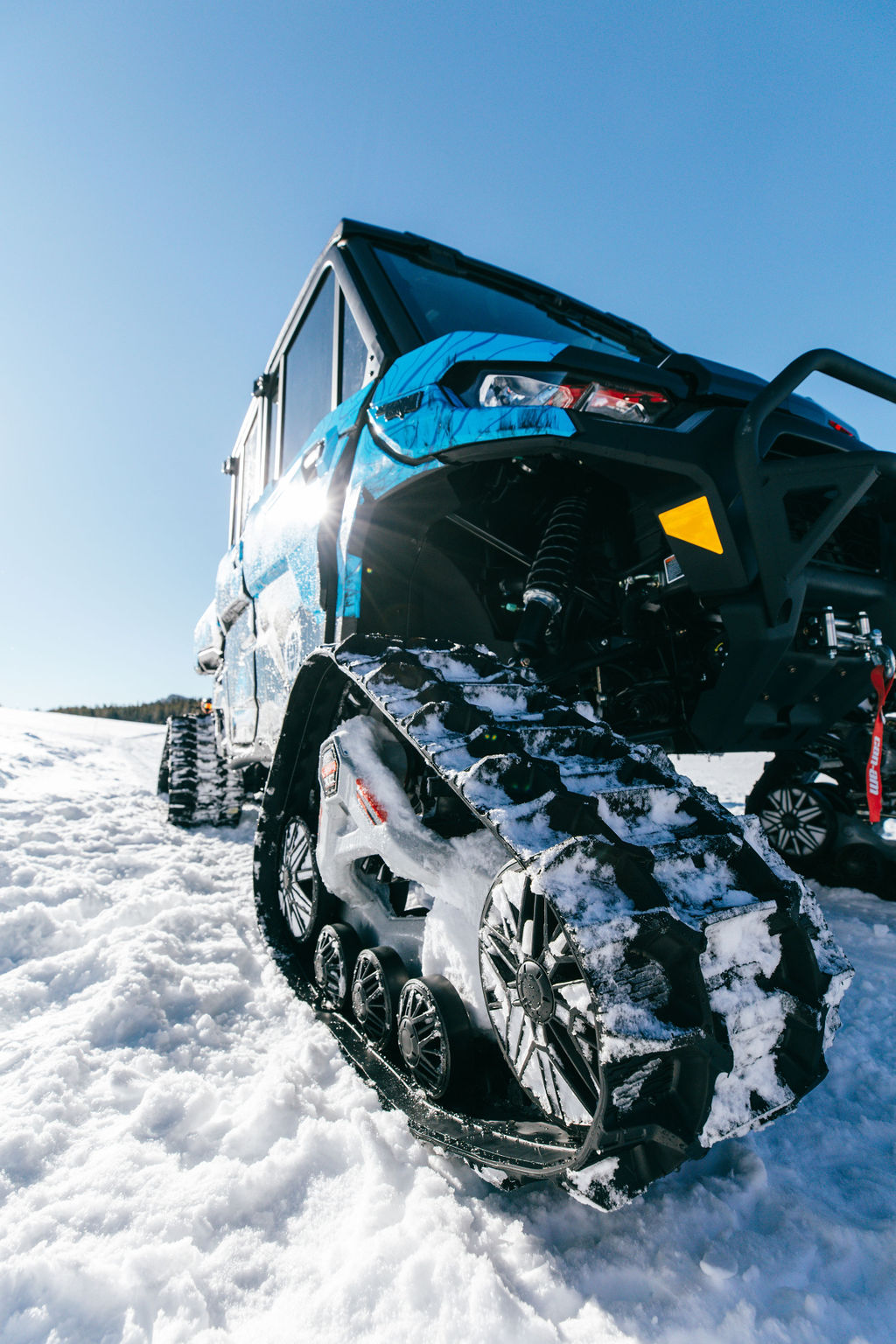 A close up of the Can-Am Apache XC LT track system on a Defender in the snow.