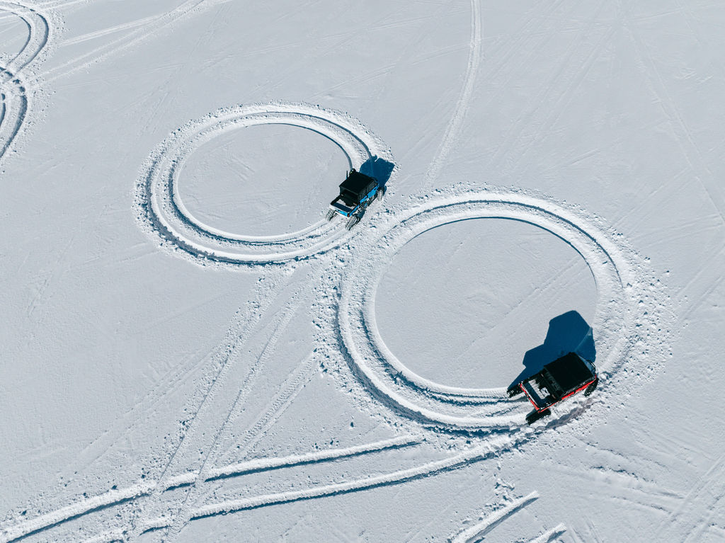 An overhead view of two circles in the snow made by two different side-by-sides.