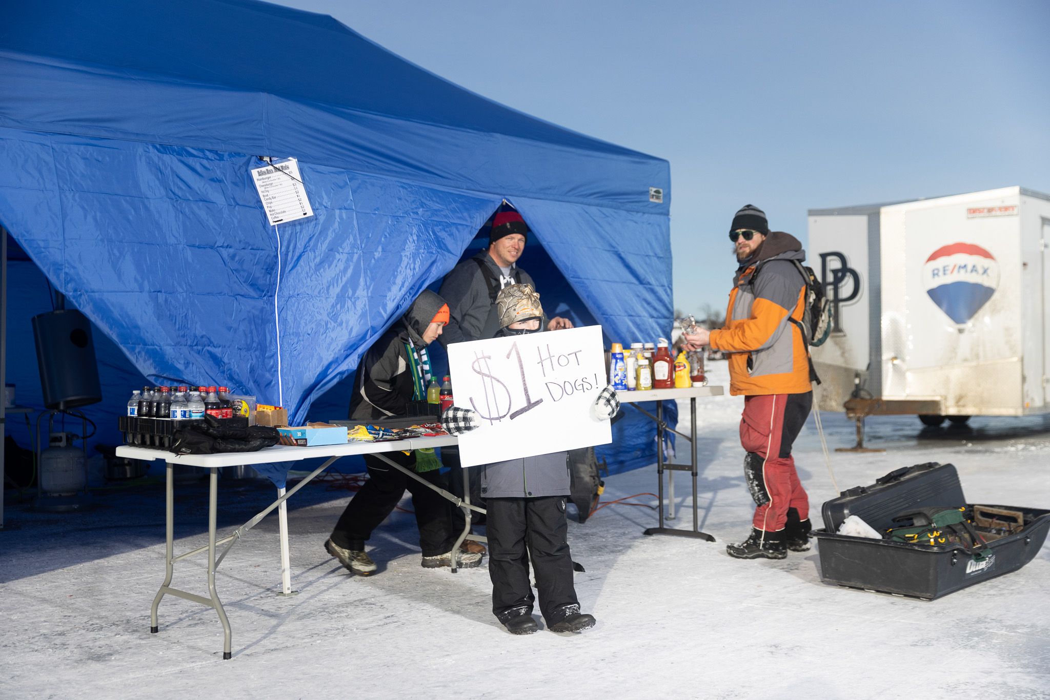 A small kid holds up a sign that says $1 hot dogs.