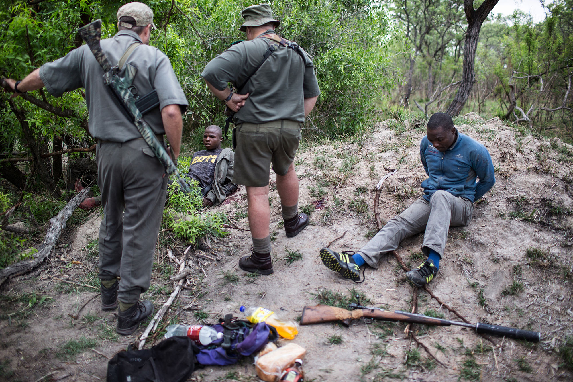 KRUGER NATIONAL PARK, SOUTH AFRICA NOVEMBER 7 (SOUTH AFRICA OUT): Rangers Rob Thompson and Don English with suspected rhino poachers on November 7, 2014 at the Kruger National Park, South Africa. The suspected rhino poachers were in possession of a .375 hunting rifle fitted with a silencer, as well as an array of machetes and knives. A Special Ranger Patrol is conducting a military-style campaign to combat the scourge of rhino poaching. (Photo by James Oatway/Sunday Times/Gallo Images/Getty Images)