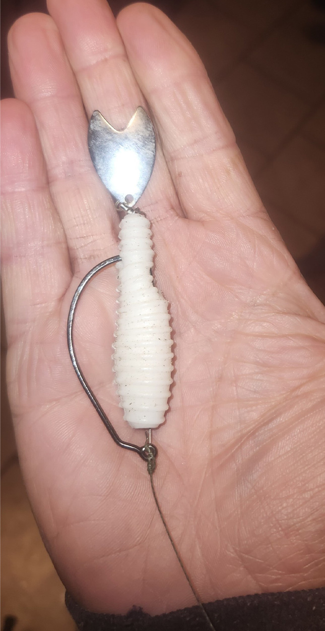 A white fishing lure in a man's palm.