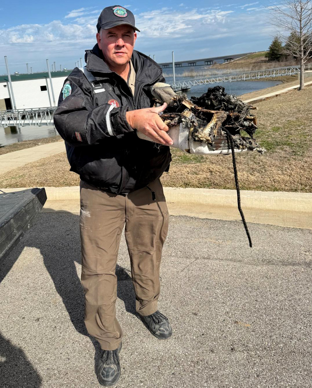 A Texas game warden holds up the remains of a charred cooler.