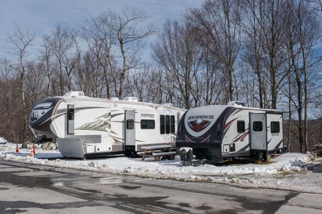 A fifth-wheel and a travel trailer camping in the snow.